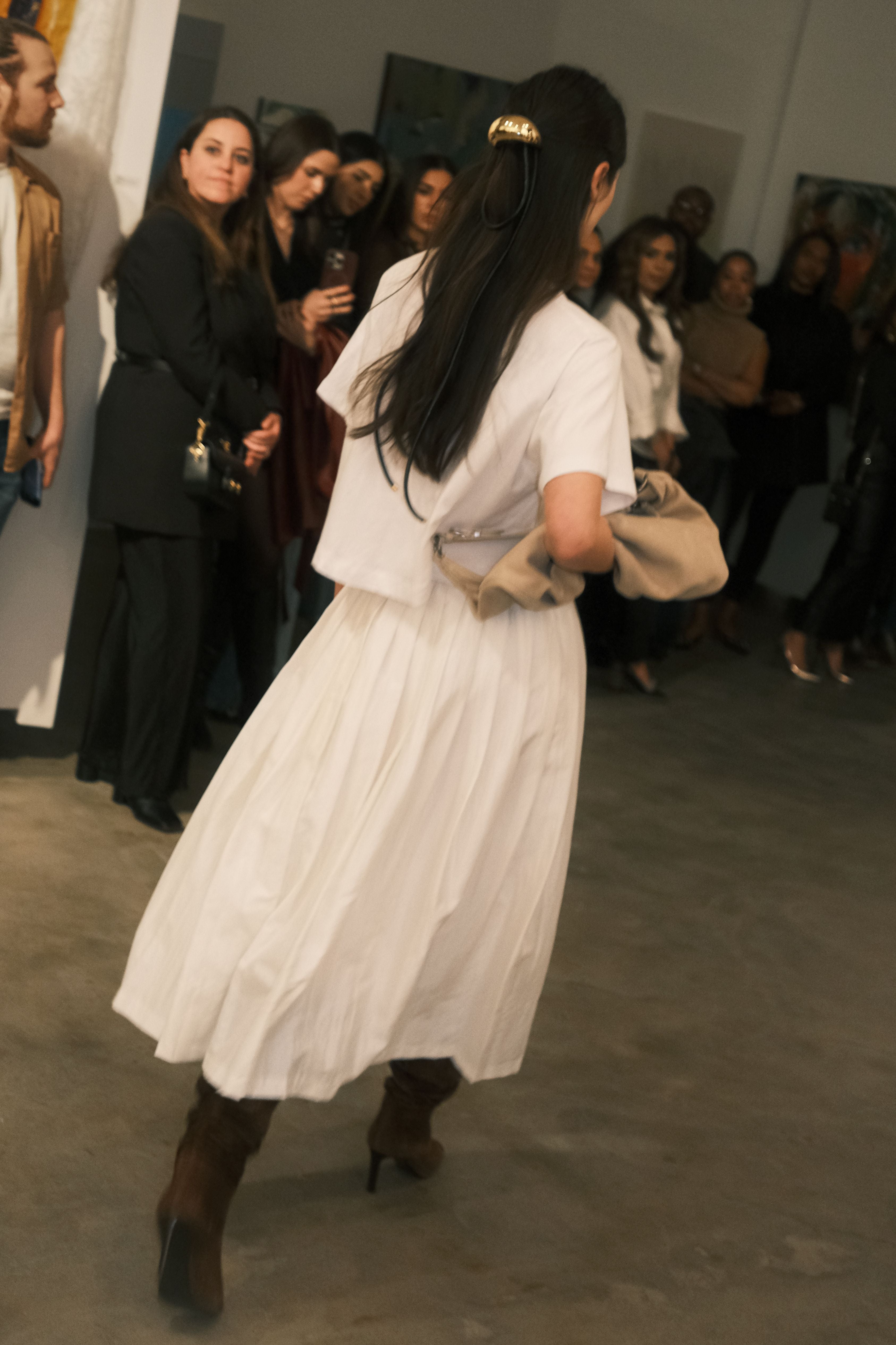 A person wearing a white pleated full skirt with an elastic waistband, standing and facing to the side.