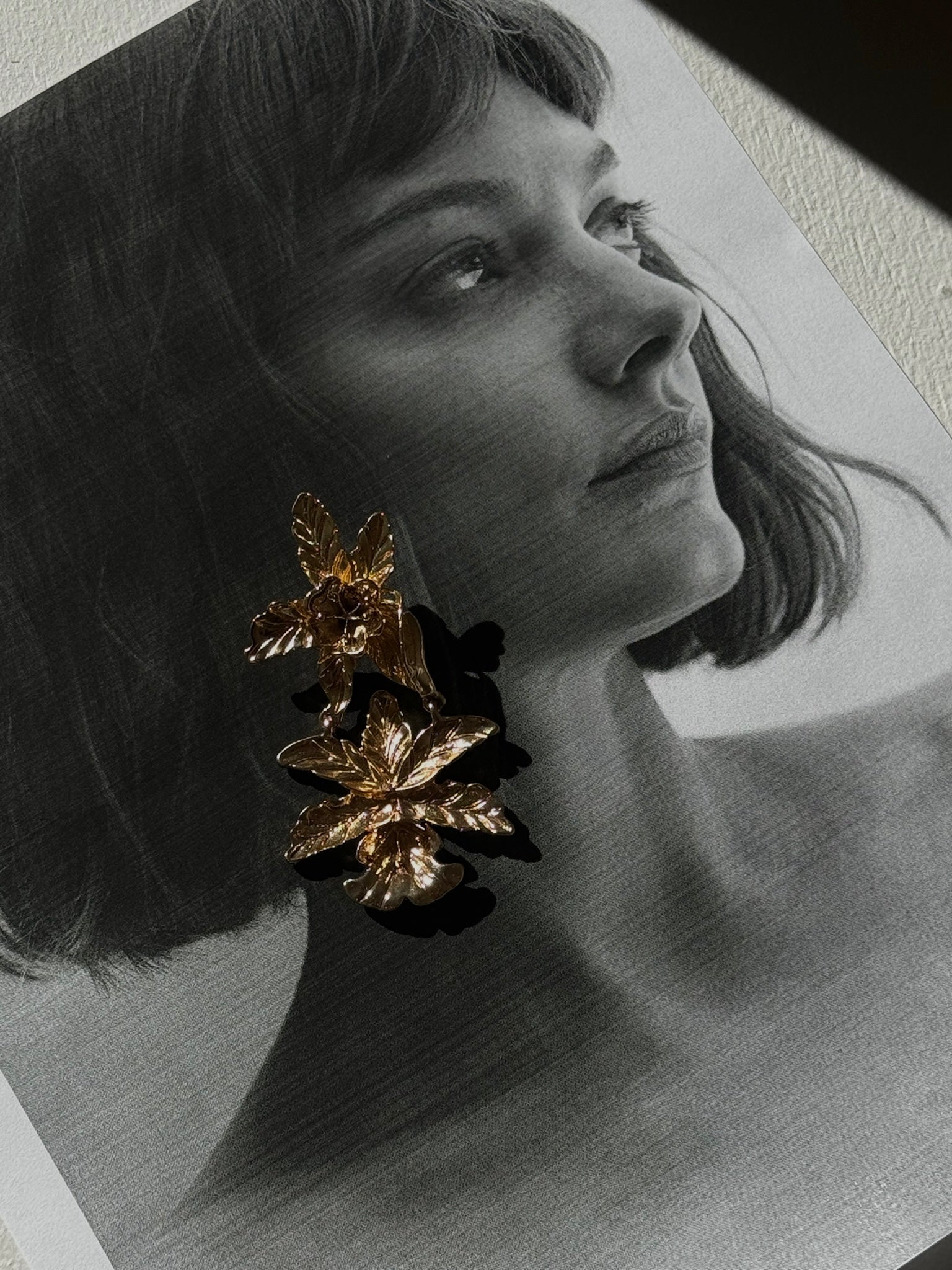 Woman wearing gold leaf earrings in a close-up portrait.