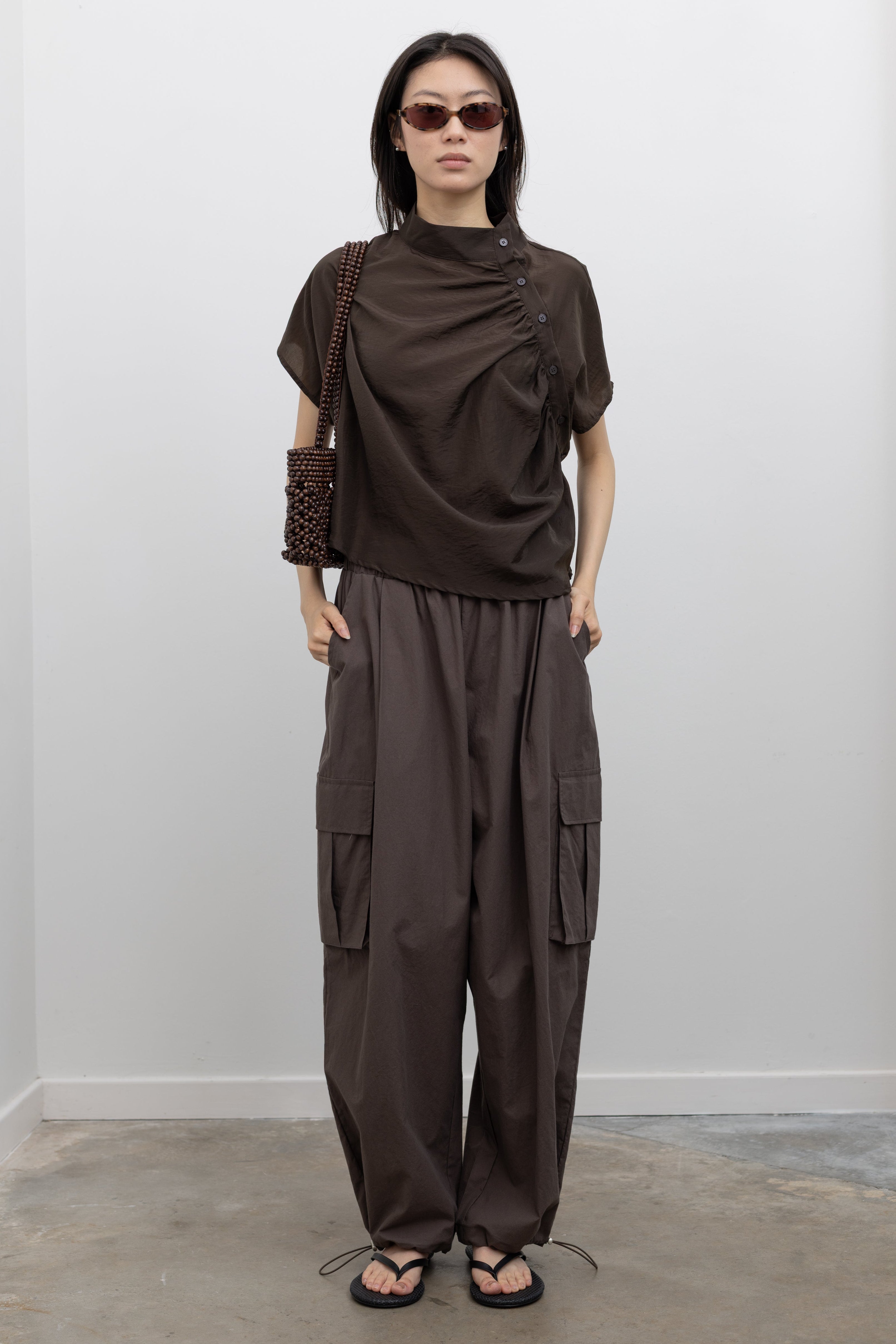 Alas Eius breathable cotton cargo pants with wide leg shape, drawstring waist, and ankle bungee cords, styled as relaxed resort wear pants and versatile travel essentials at Alas Eius