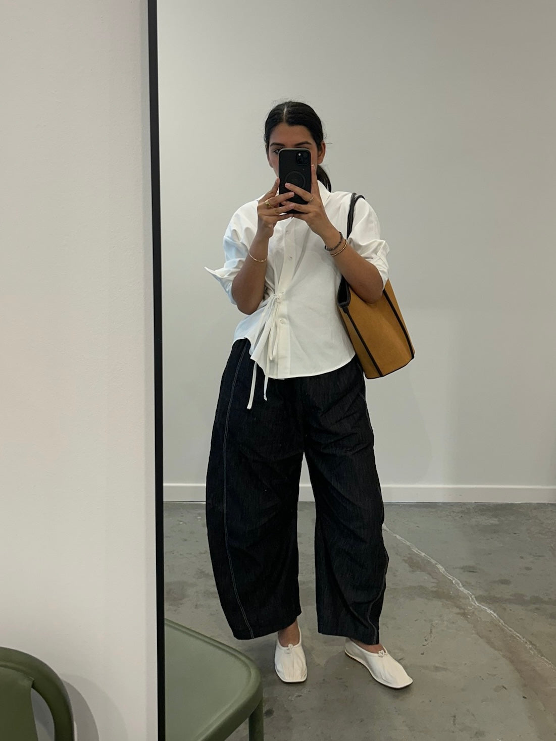 Person taking a mirror selfie wearing a white shirt, black pants, and white shoes.