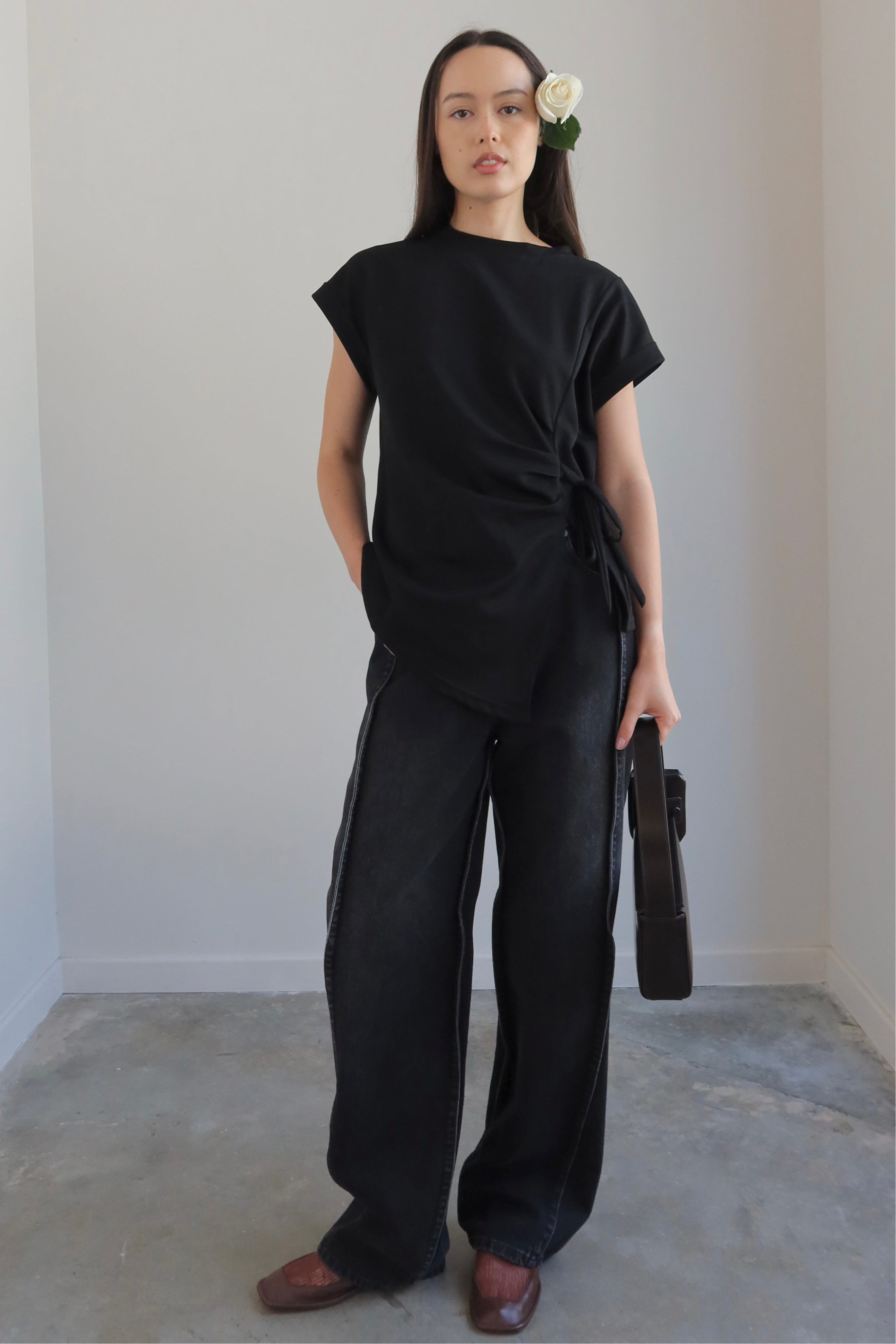 Woman wearing a black outfit with wide-leg pants against a plain background