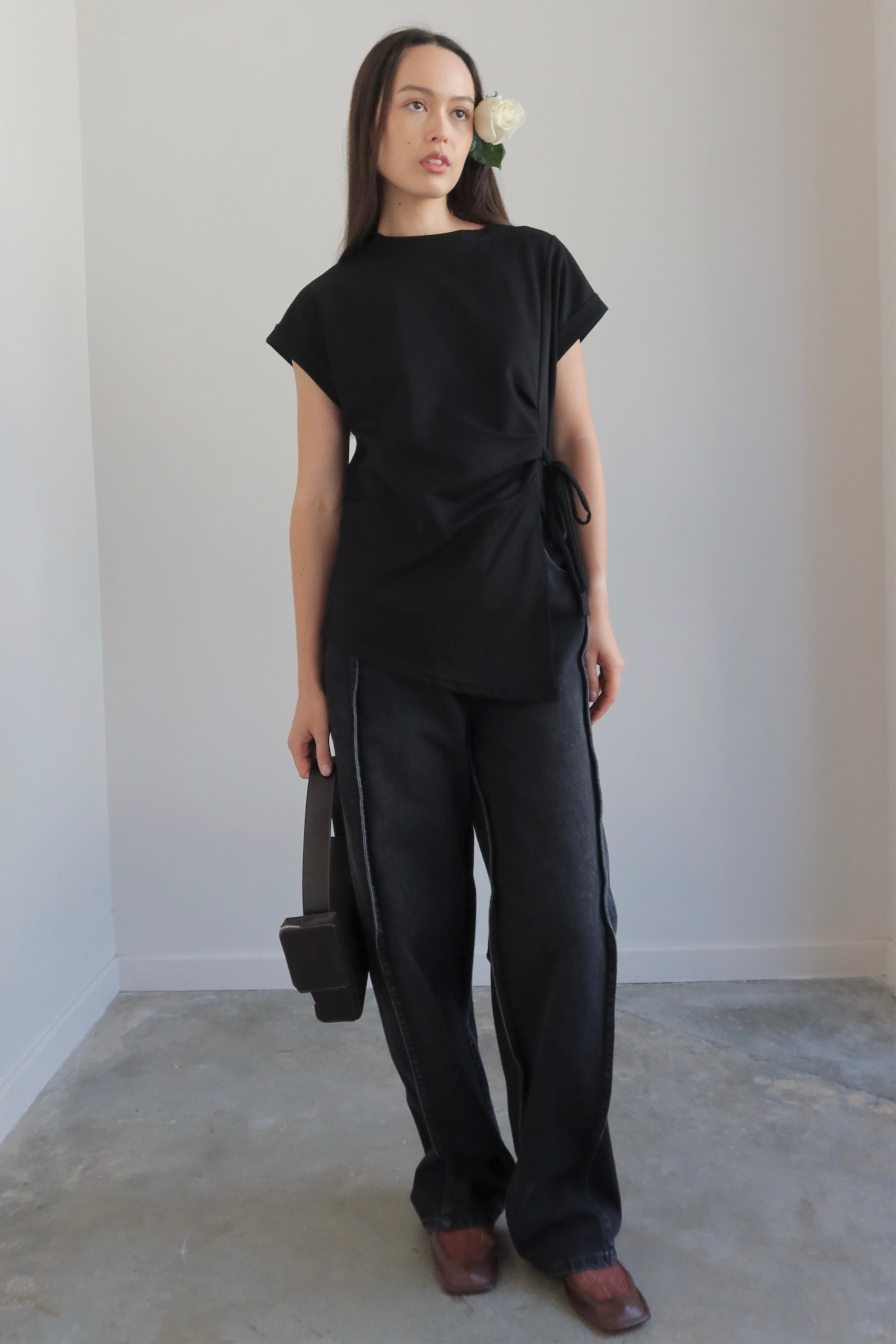 Person wearing a black outfit standing against a plain background