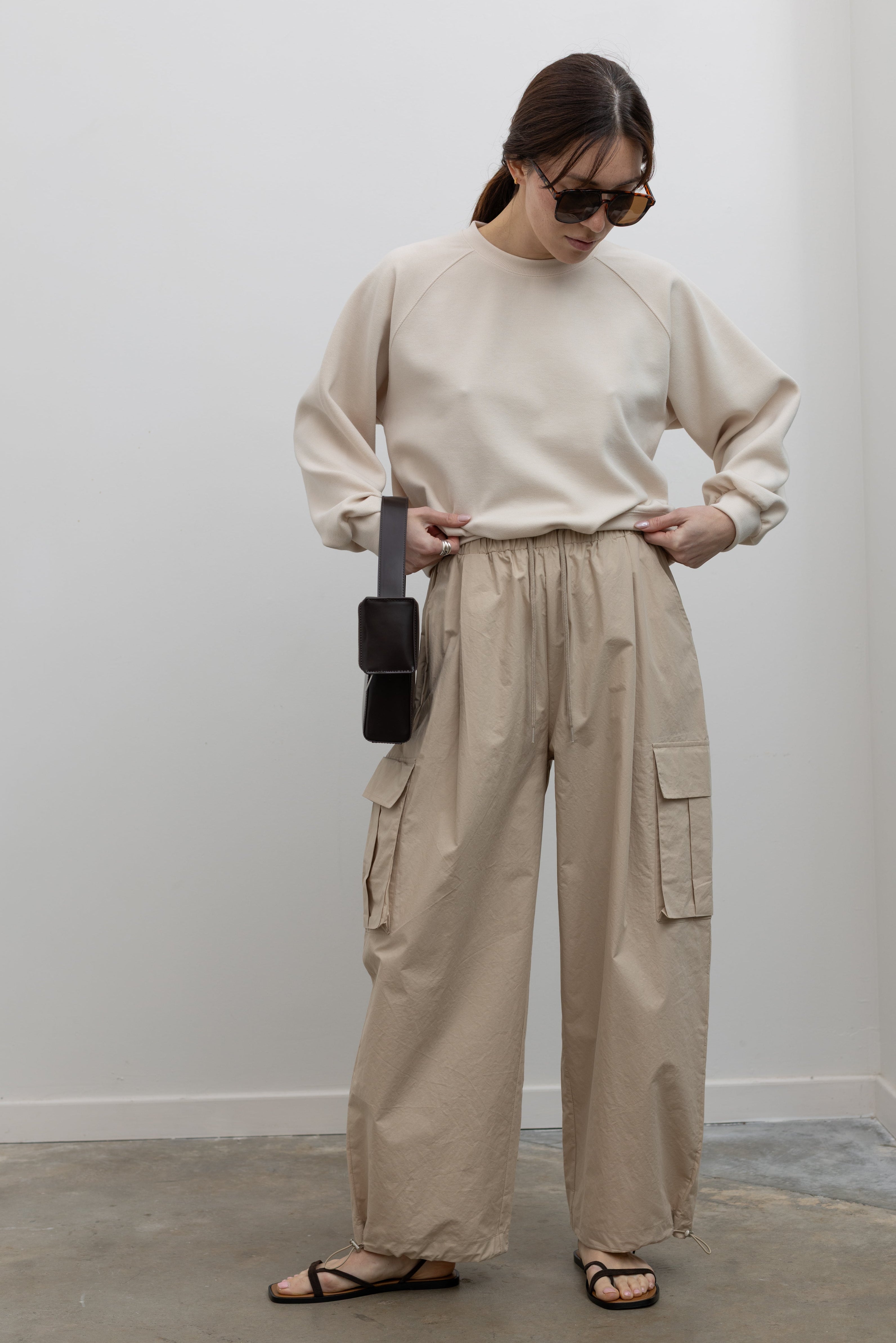 Woman wearing Alas Eius Brand Cream Raglan long-sleeved crewneck Sweatshirt with khaki cargo pants and sunglasses at Alas Eius