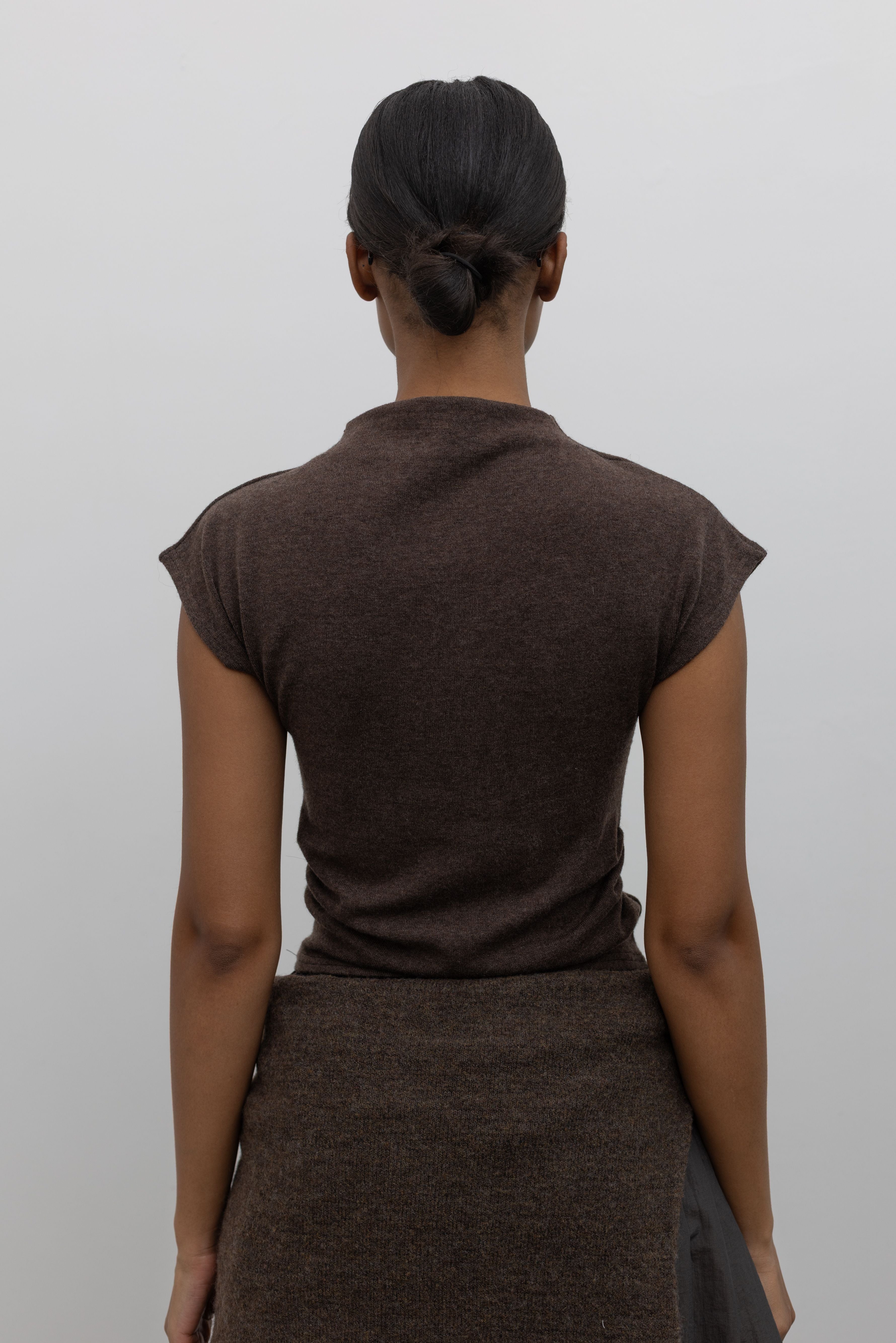 Back view of a woman wearing a vintage inspired top in an Alas Eius label brown mock neck knit slim fit top with flattering cap sleeves at Alas Eius