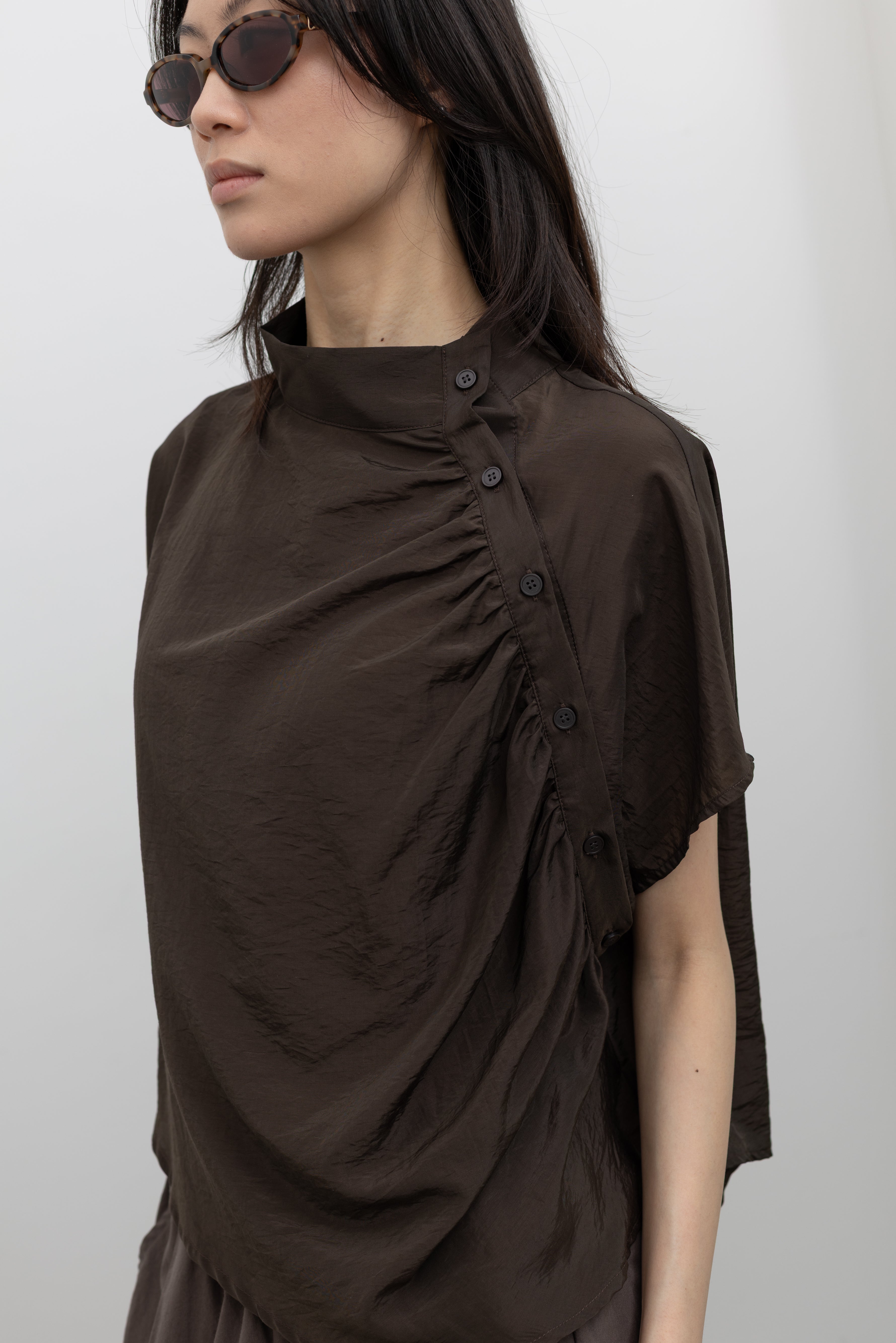 Alas Eius elegant draped top with mock neckline, side button accents, and fluid relaxed silhouette, styled as a women’s smart casual blouse for effortless transitional dressing at Alas Eius