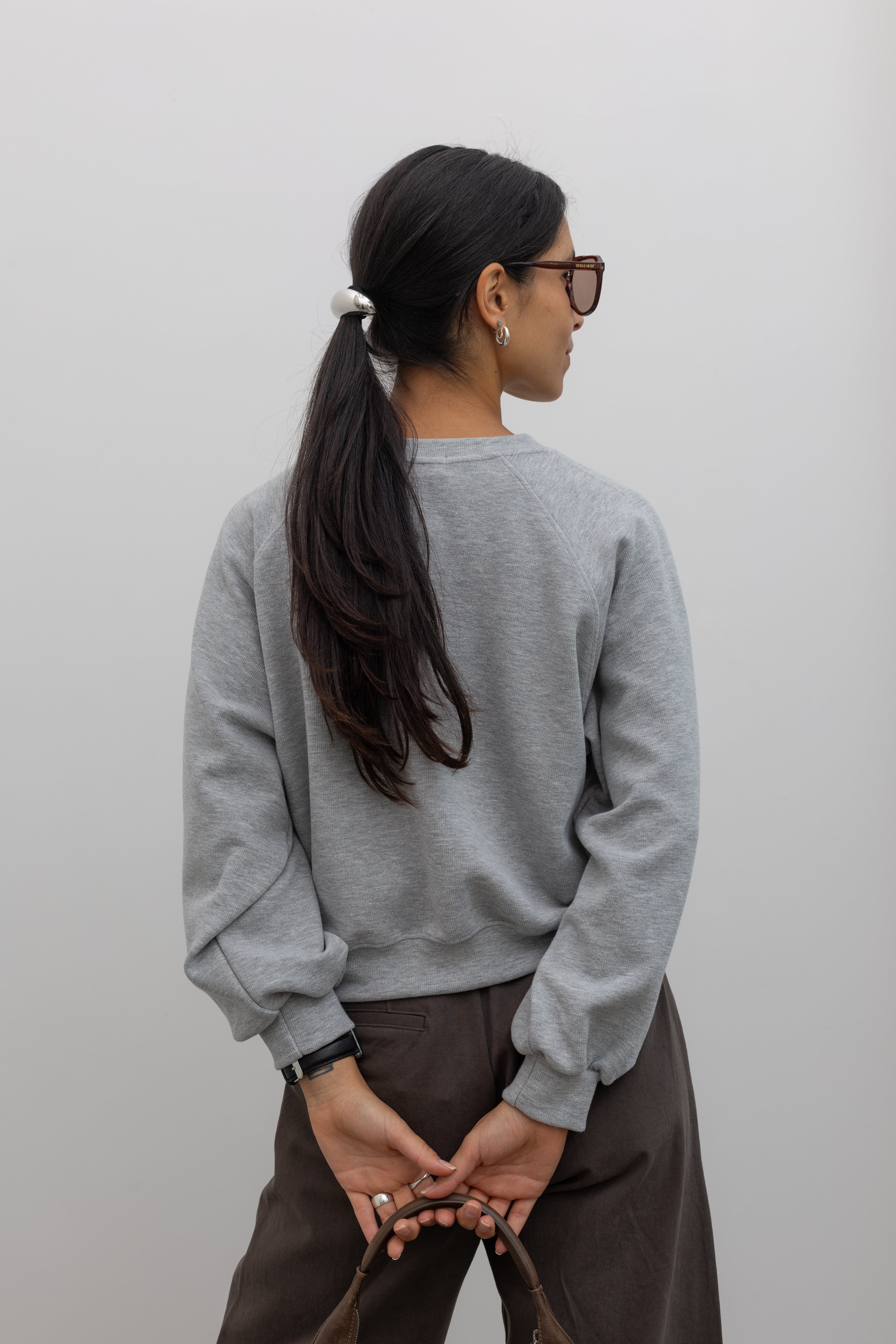 Back neckline view of Woman wearing everyday style in a Alas Eius label Heather gray raglan sleeve elevated essentials sweatshirt