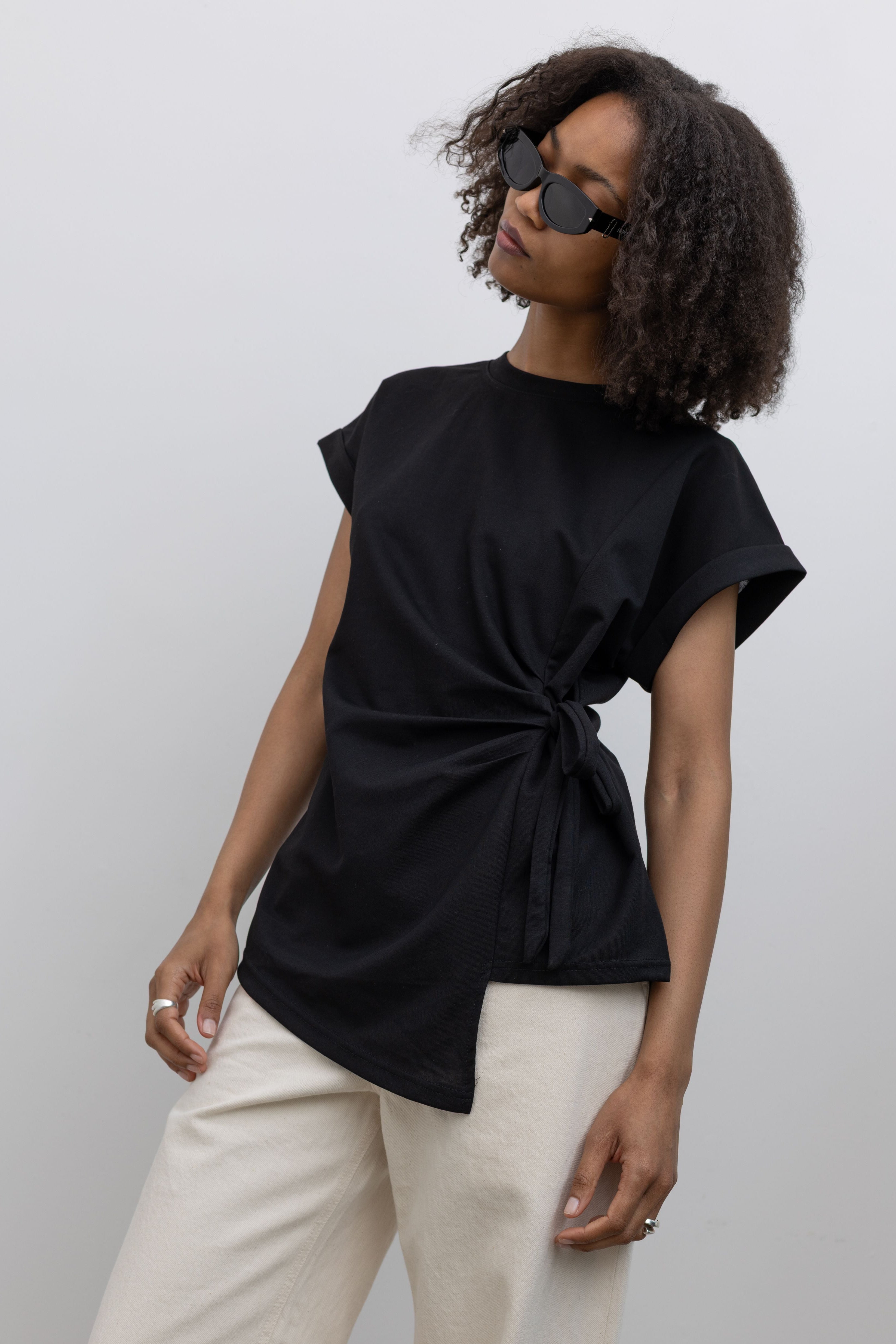 Close-up of the customizable side tie and elegant waist ruching on an Alas Eius label elevated black crewneck tee.