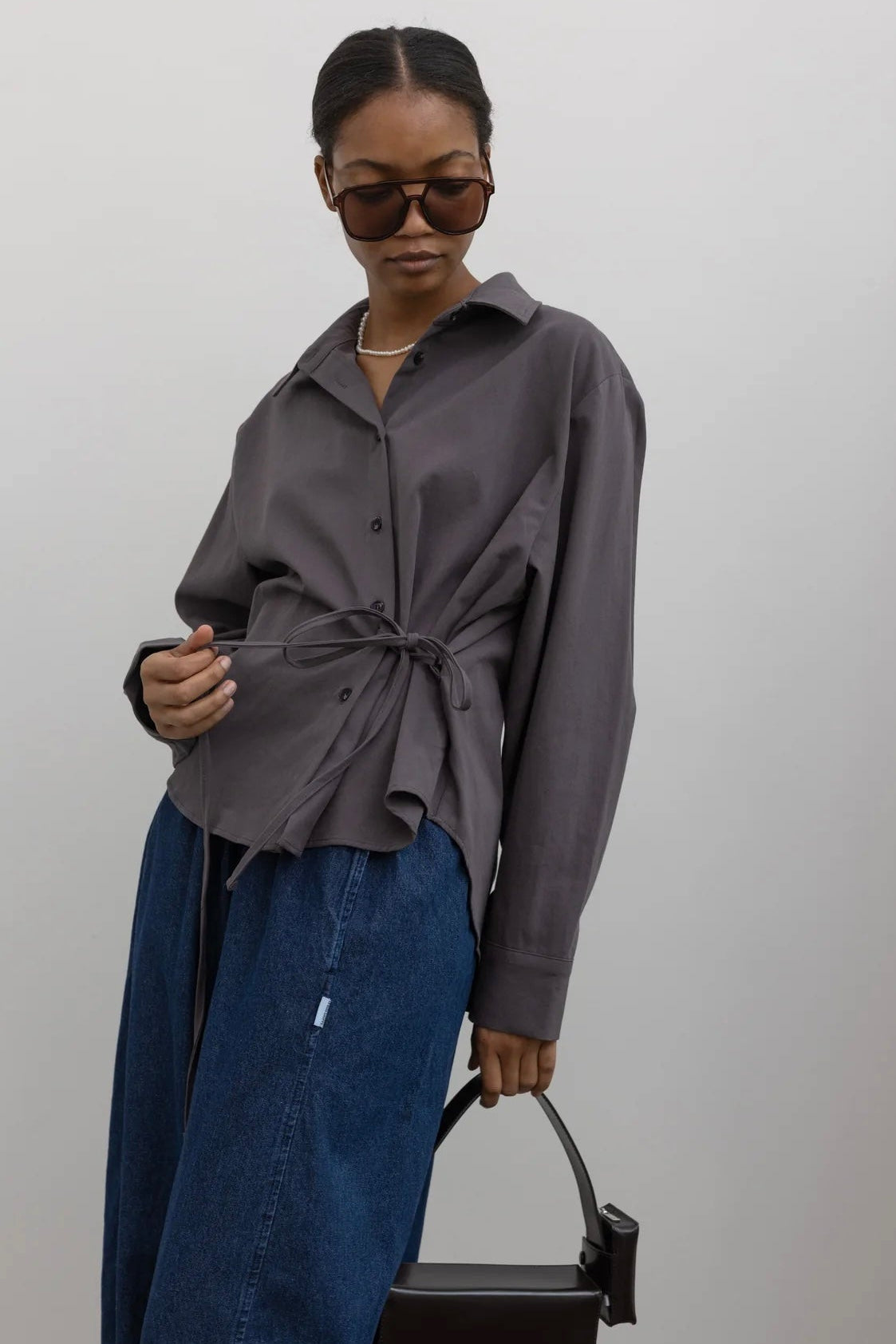 Woman wearing capsule wardrobe essential in an elegant and flattering Alas Eius label brushed cotton cinched waist button down collared long sleeve top with denim and accessories at Alas Eius
