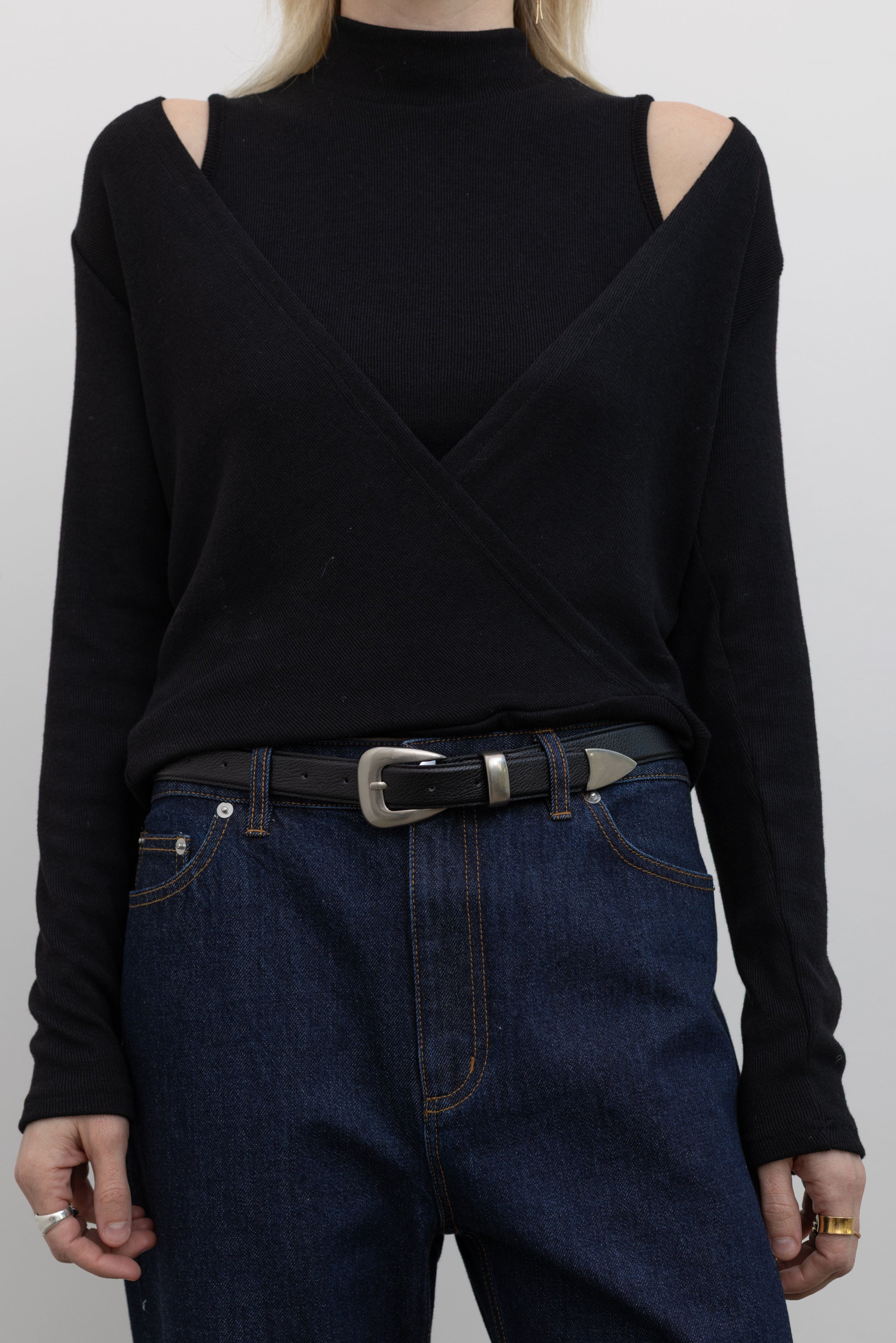 Product view of Woman wearing Alas Euis label deep v-neck double layer long sleeve black knit top with mock neck and open shoulders paired with Tibi dark wash jeans at alas eius