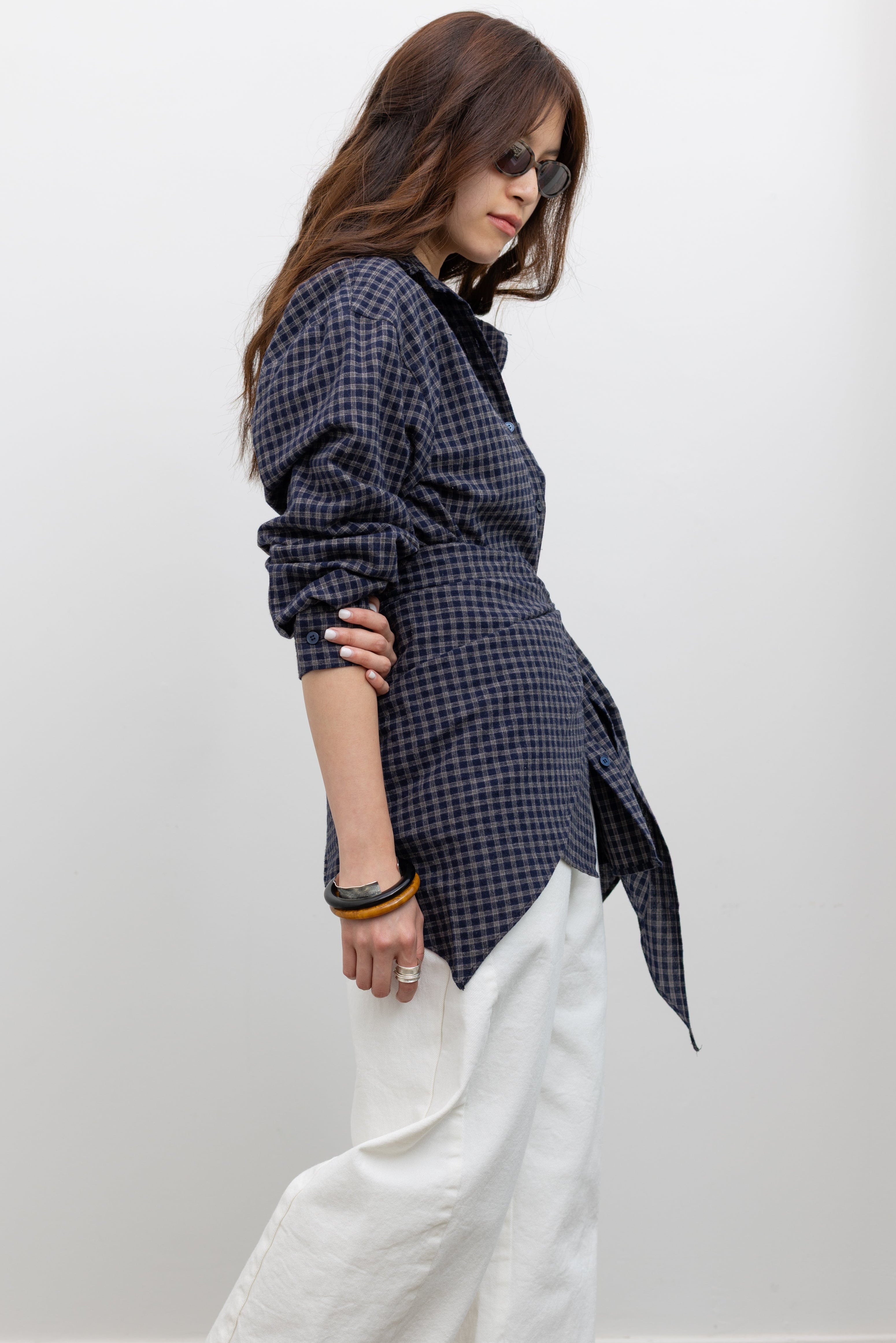 Alas Eius label oversized navy blue and tan plaid button-down top styled with coordinating bandana scarf around waist for a flattering cinched look paired with white denim jeans at Alas Eius. 