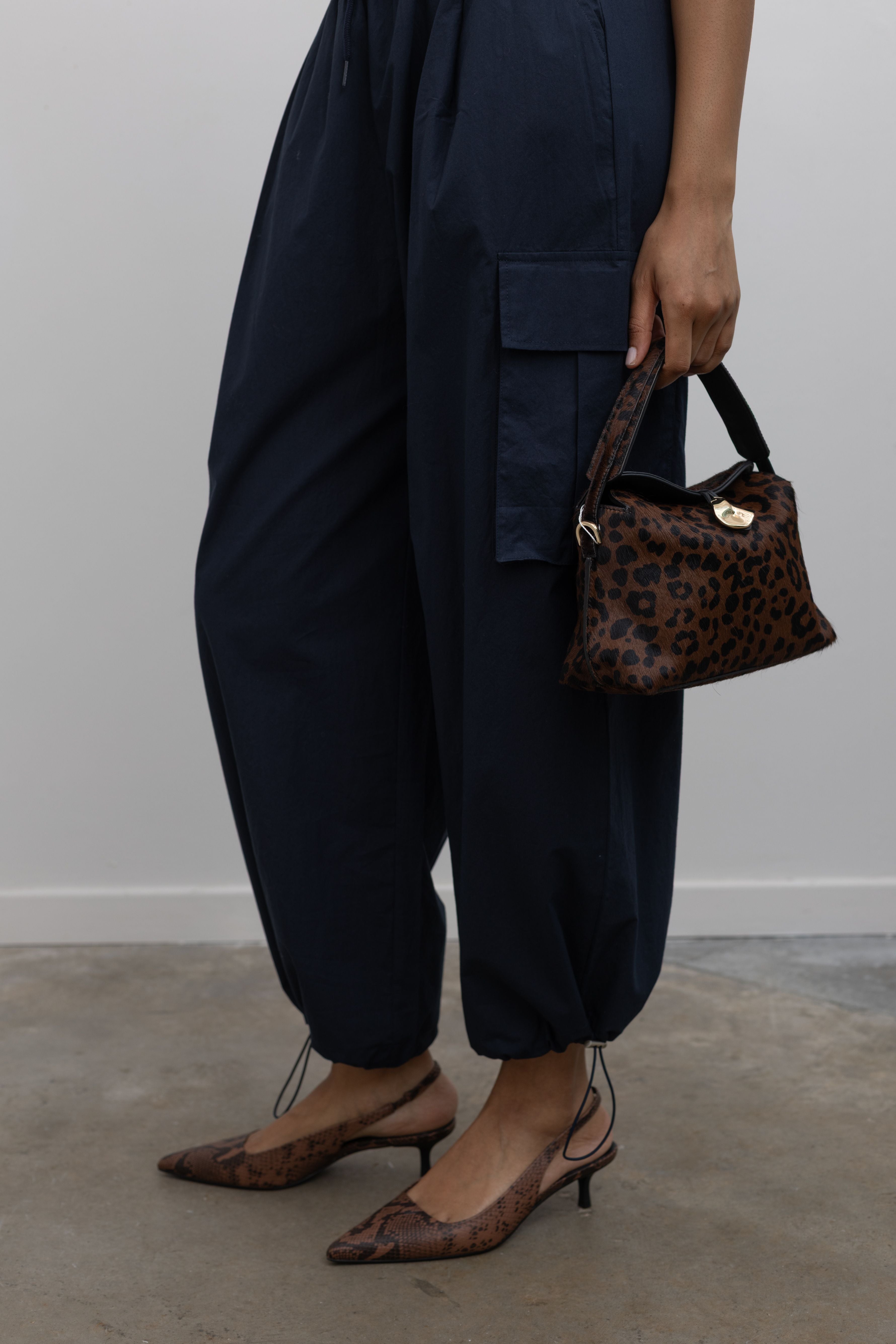 Close-up of cinched drawstring ankles and pockets on a pair of Alas Eius Label navy blue lightweight cotton wide leg cargo pants. Featuring an oversized fit with drawstring ankles, a tie waist, and extra pockets on the legs at Alas Eius.