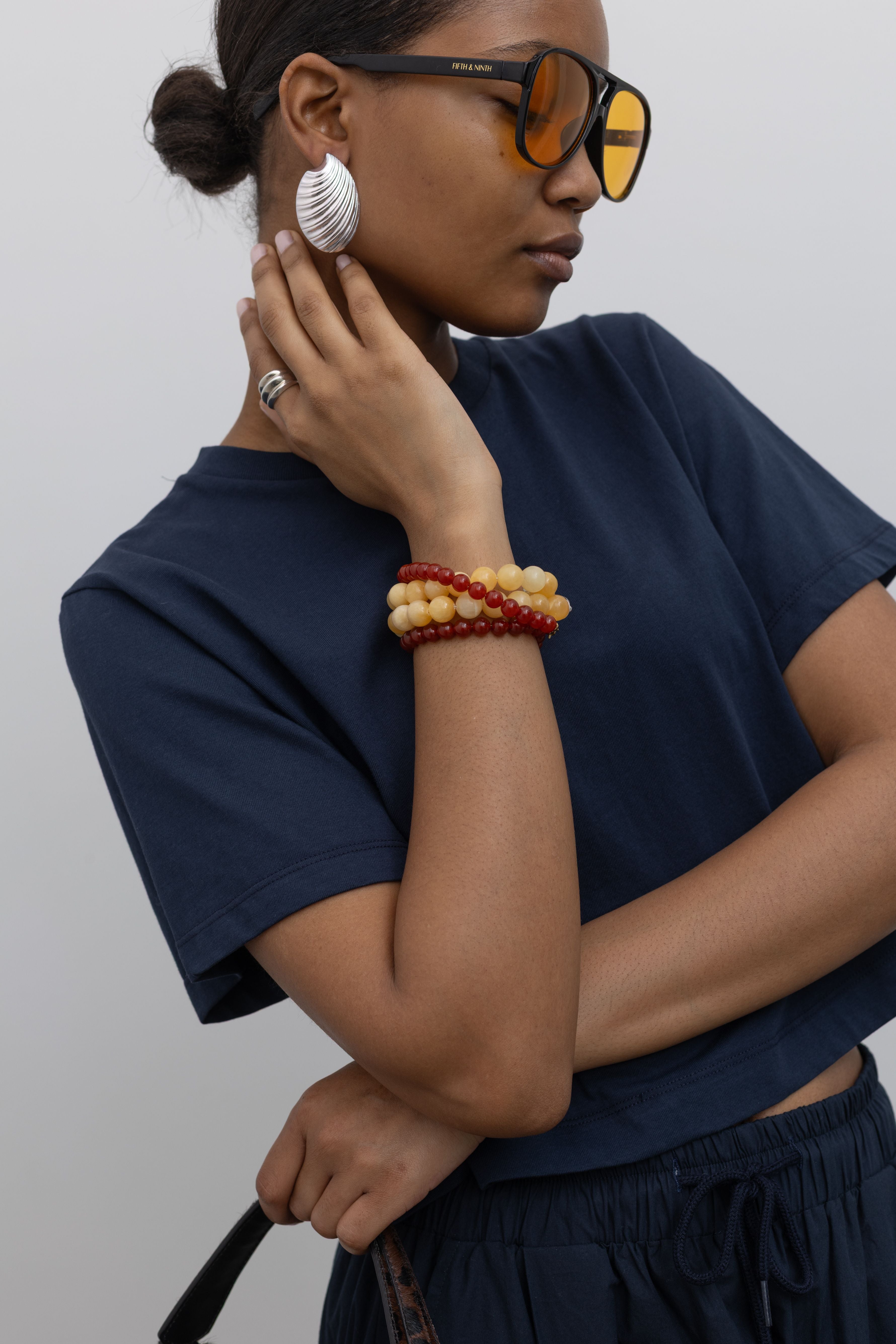 Detailed product view of woman standing wearing everyday essential style in an Alas Eius Label Navy Blue Relaxed Cropped Short Sleeved T-Shirt with sunglasses and accessories at Alas Eius.