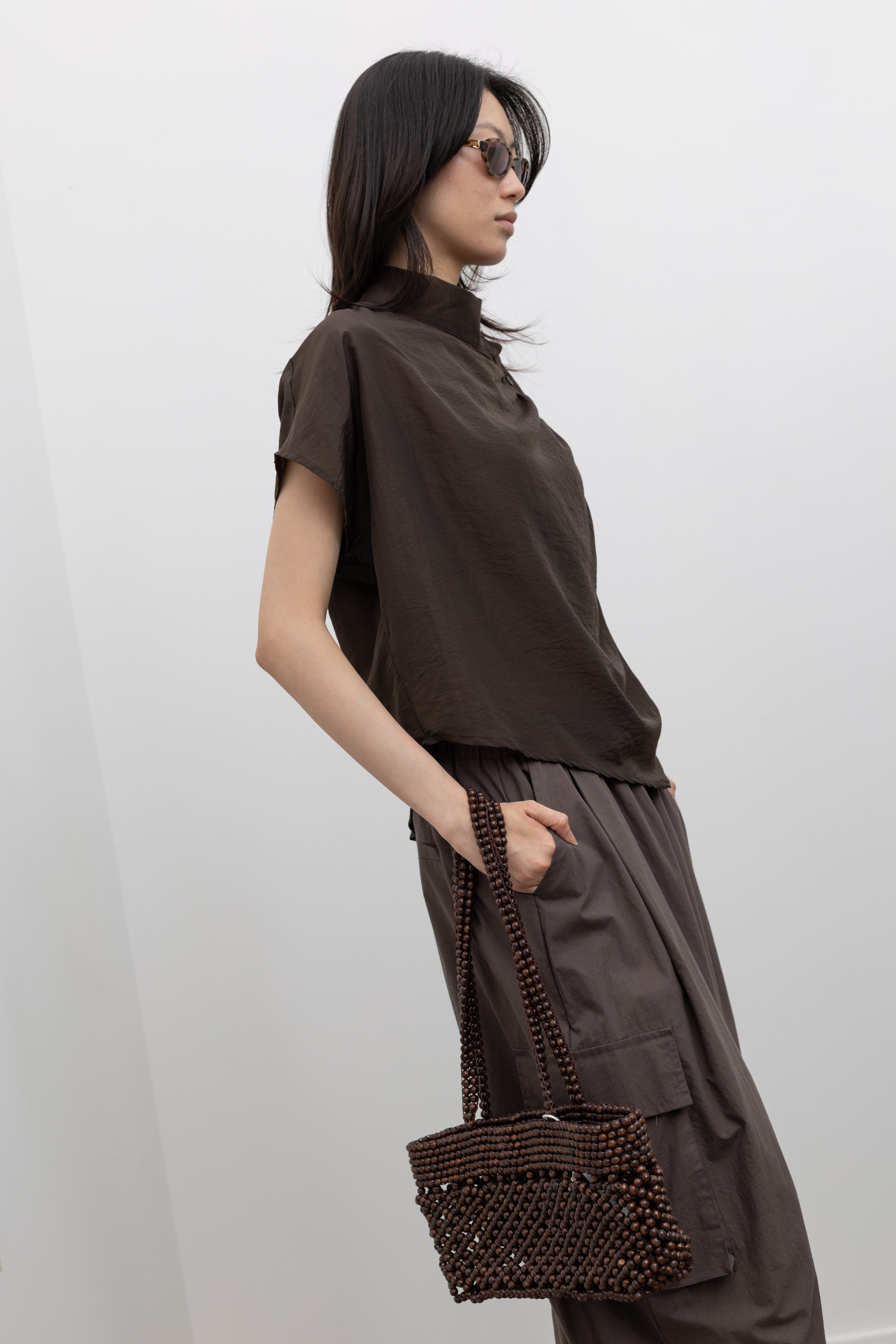 Alas Eius minimal mock neck blouse with softly draped silhouette, refined side button detail, and relaxed fit, styled as a modern women’s workwear top for polished office looks at Alas Eius