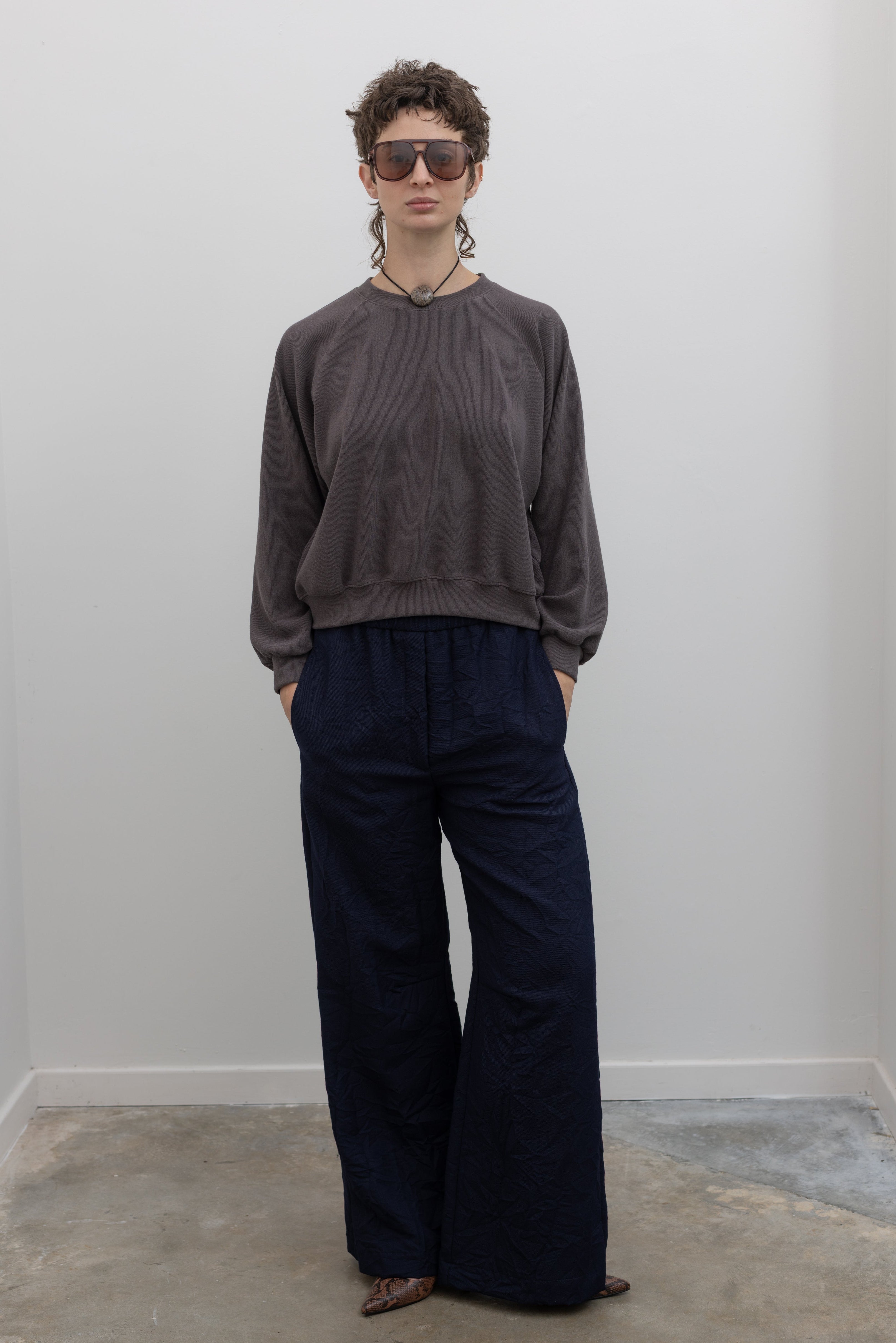 Mocha brown raglan sleeve sweatshirt with relaxed fit, styled with navy blue pants on model against a neutral background