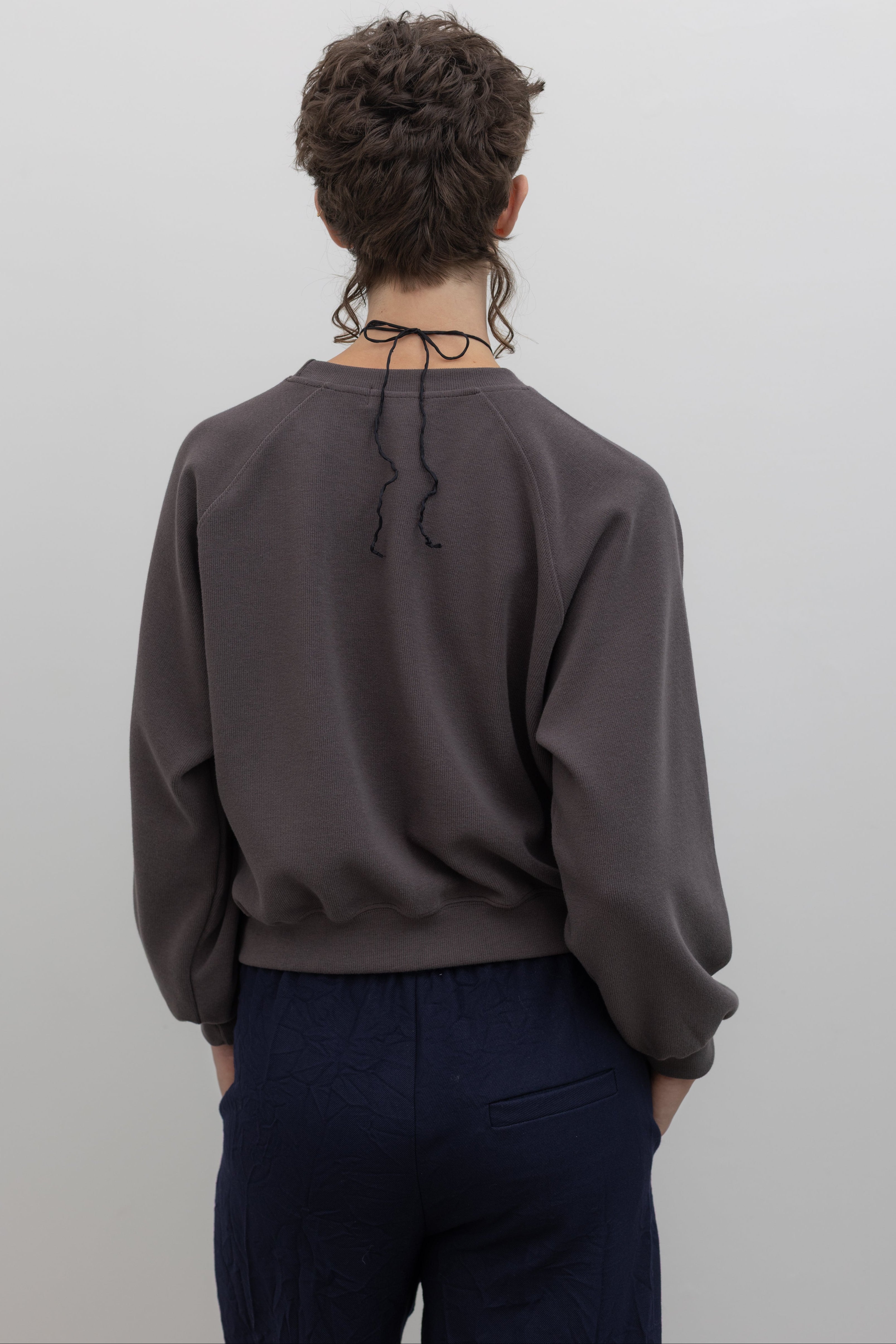 Mocha brown raglan sleeve sweatshirt with relaxed fit, styled on model against a neutral background, back view