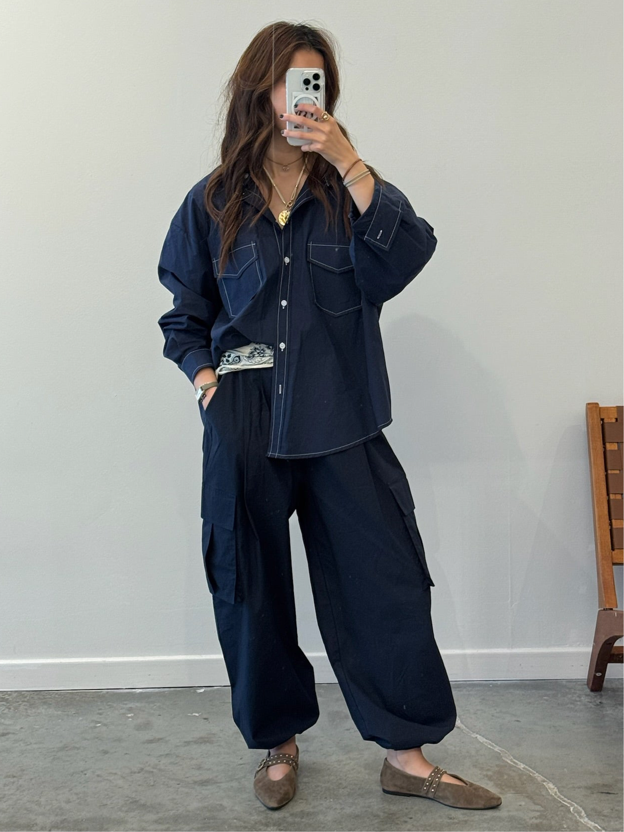 Person wearing a navy blue outfit with wide-leg pants and a jacket, standing against a plain wall.