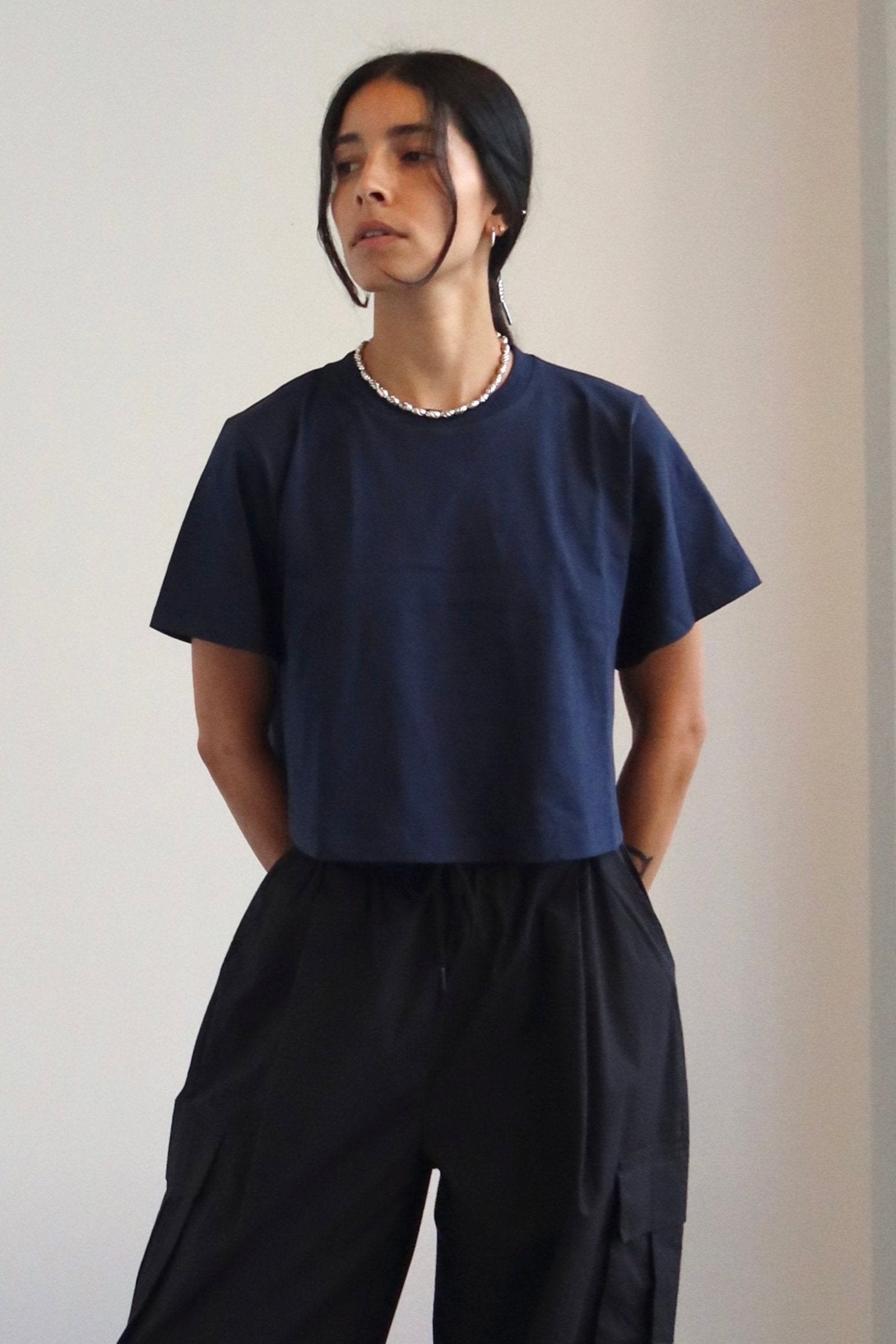 A person wearing a navy relaxed fit cropped t-shirt paired with black trousers.
