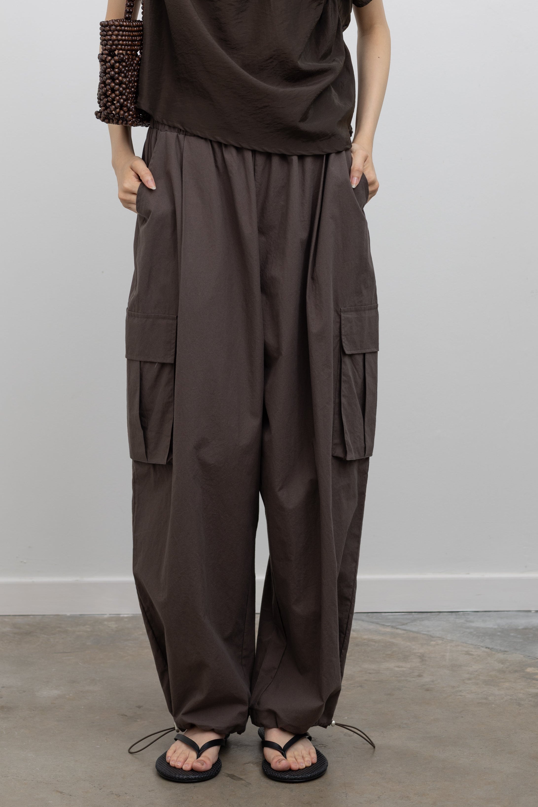 Alas Eius oversized cargo trousers crafted from breathable premium cotton with functional leg pockets and customizable fit details, styled as relaxed fit women’s bottoms for everyday wear at Alas Eius
