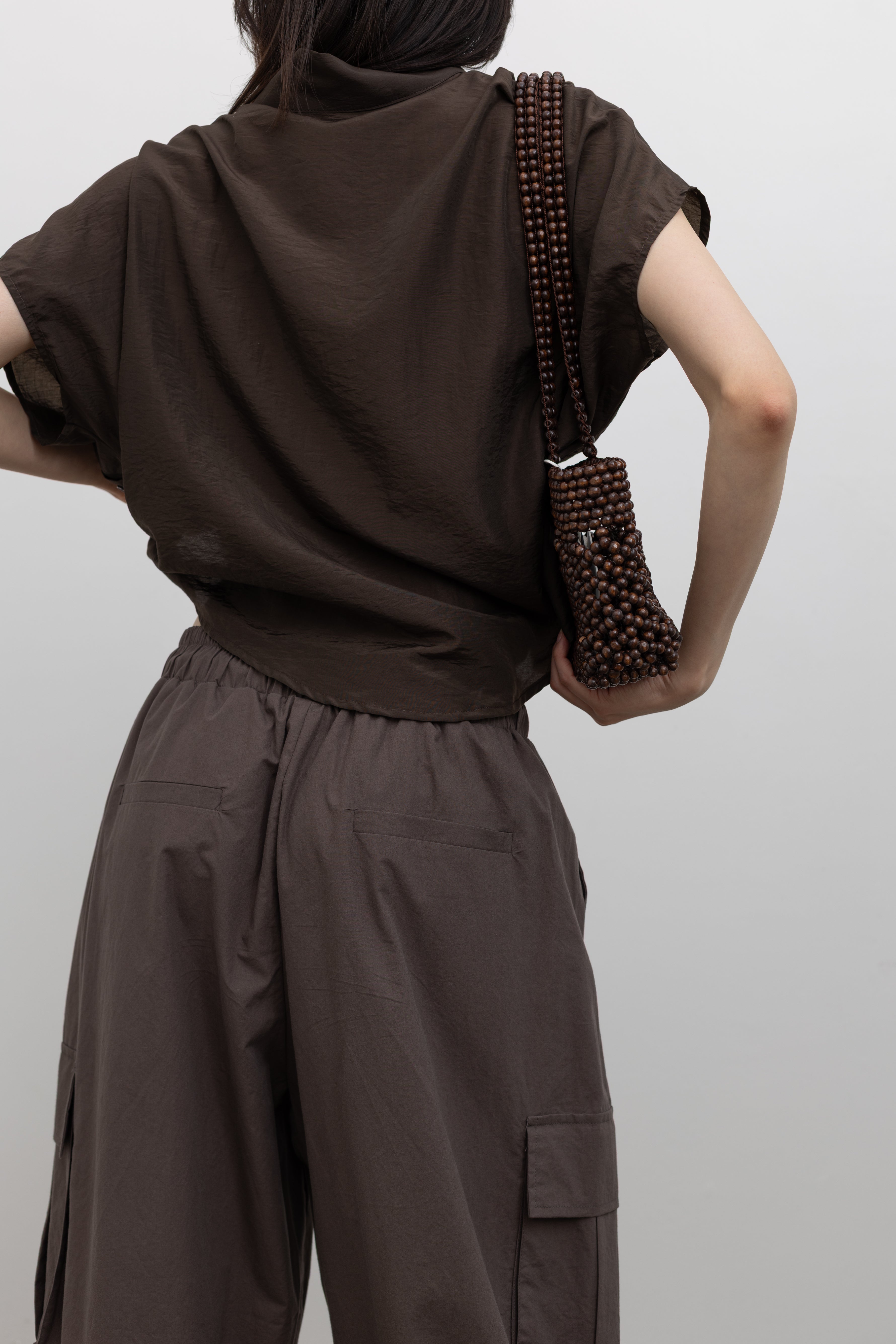 Alas Eius relaxed fit draped mock neck top with soft flowing fabric and subtle side button detailing, styled as women’s casual elegant wear paired with trousers or denim at Alas Eius