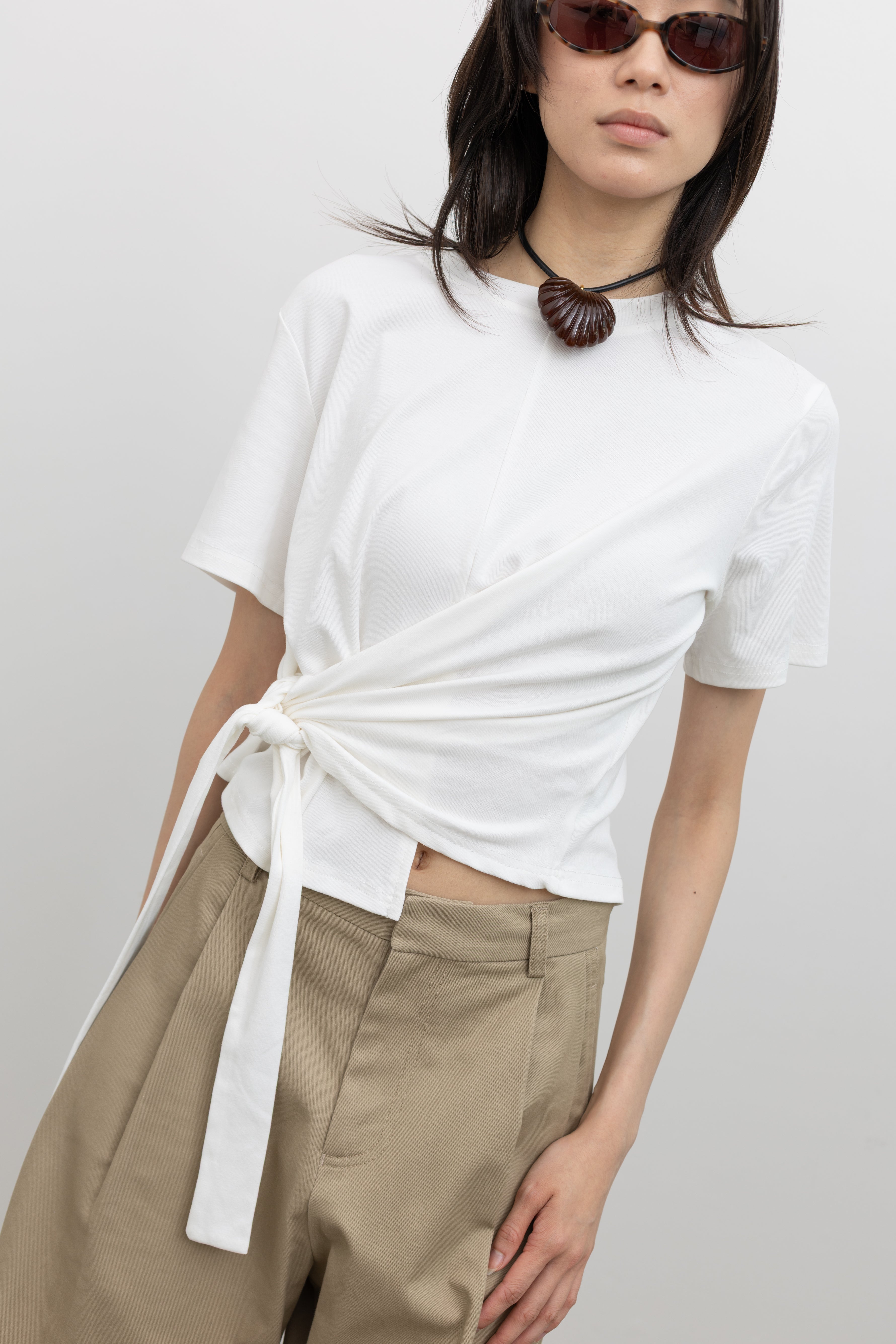 Women’s cotton blend crew neck tee with short sleeves and adjustable side tie detail creating a ruched sculptural silhouette, styled as a modern minimalist wardrobe essential at Alas Eius