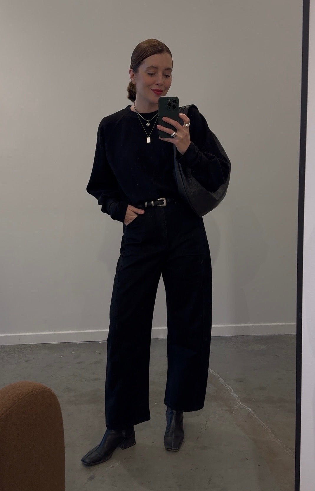 A woman wearing a black raglan sleeve sweatshirt with a round neckline and long sleeves, paired with a dark skirt.