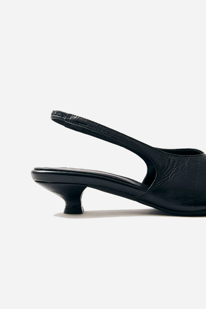 Back view of Alohas slingback pumps showing elasticated strap and sleek low-profile heel design in black leather at Alas Eius