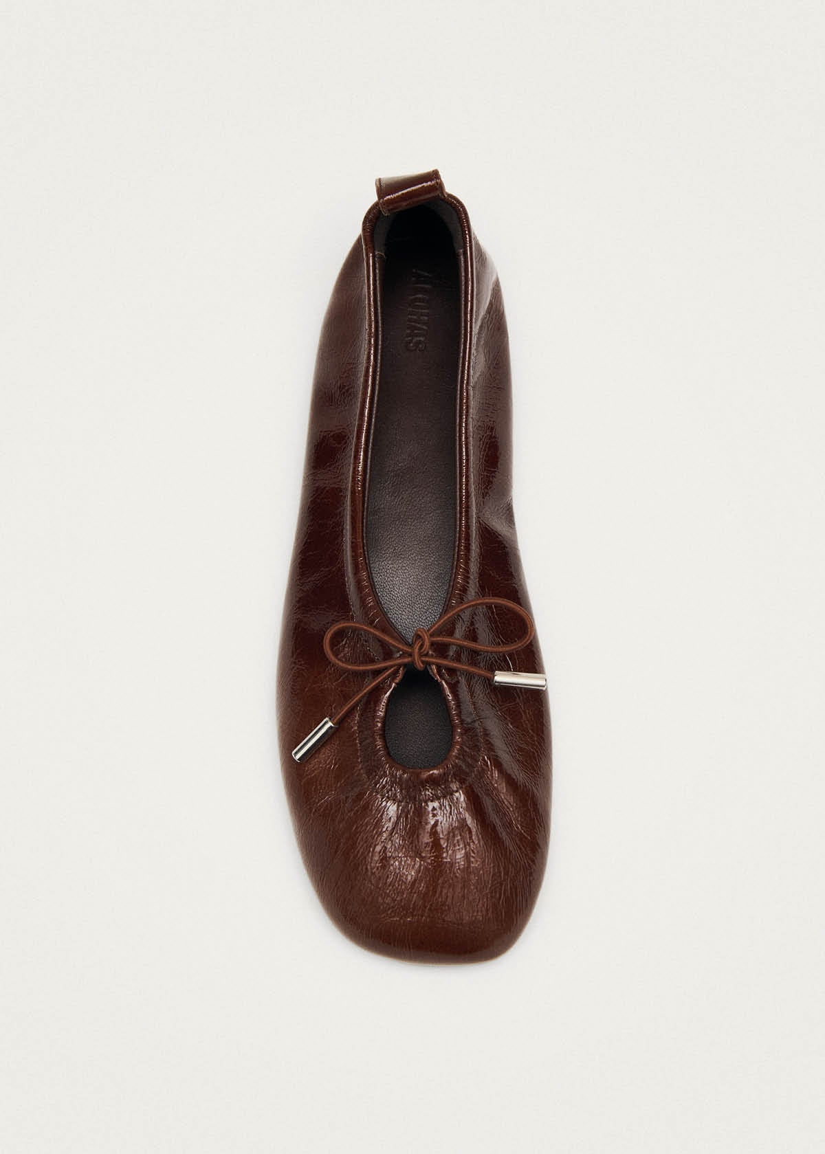 Close-up of Alohas brown patent leather ballet flat showing elasticized back and flexible sole construction at Alas Eius 
