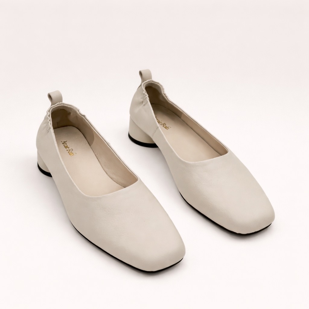 A pair timeless Amie Rafa label white leather rounded block heel glove pumps with a modern squared off toe and elastic ruched back at an Alas Eius store. 