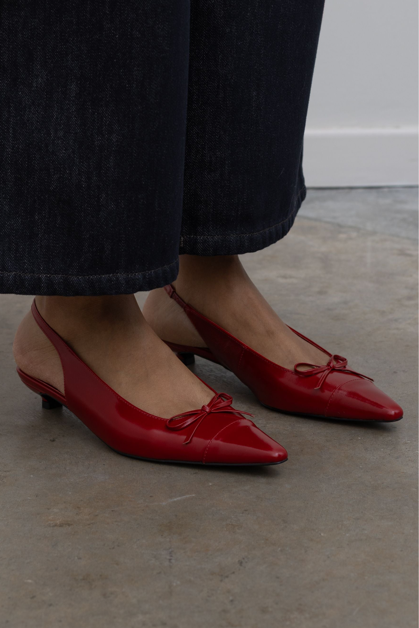 Woman wearing classic wardrobe staple in a pair of Amie Rafa Red Leather Slingback Kitten Heels with dark wash denim jeans at Alas Eius.
