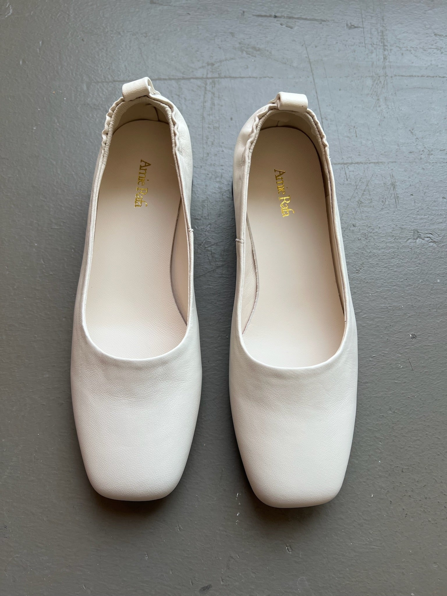 The perfect workwear pumps by Amie Rafa label featuring a white leather rounded block heel and a modern squared off toe with an elastic ruched back at an Alas Eius store. 