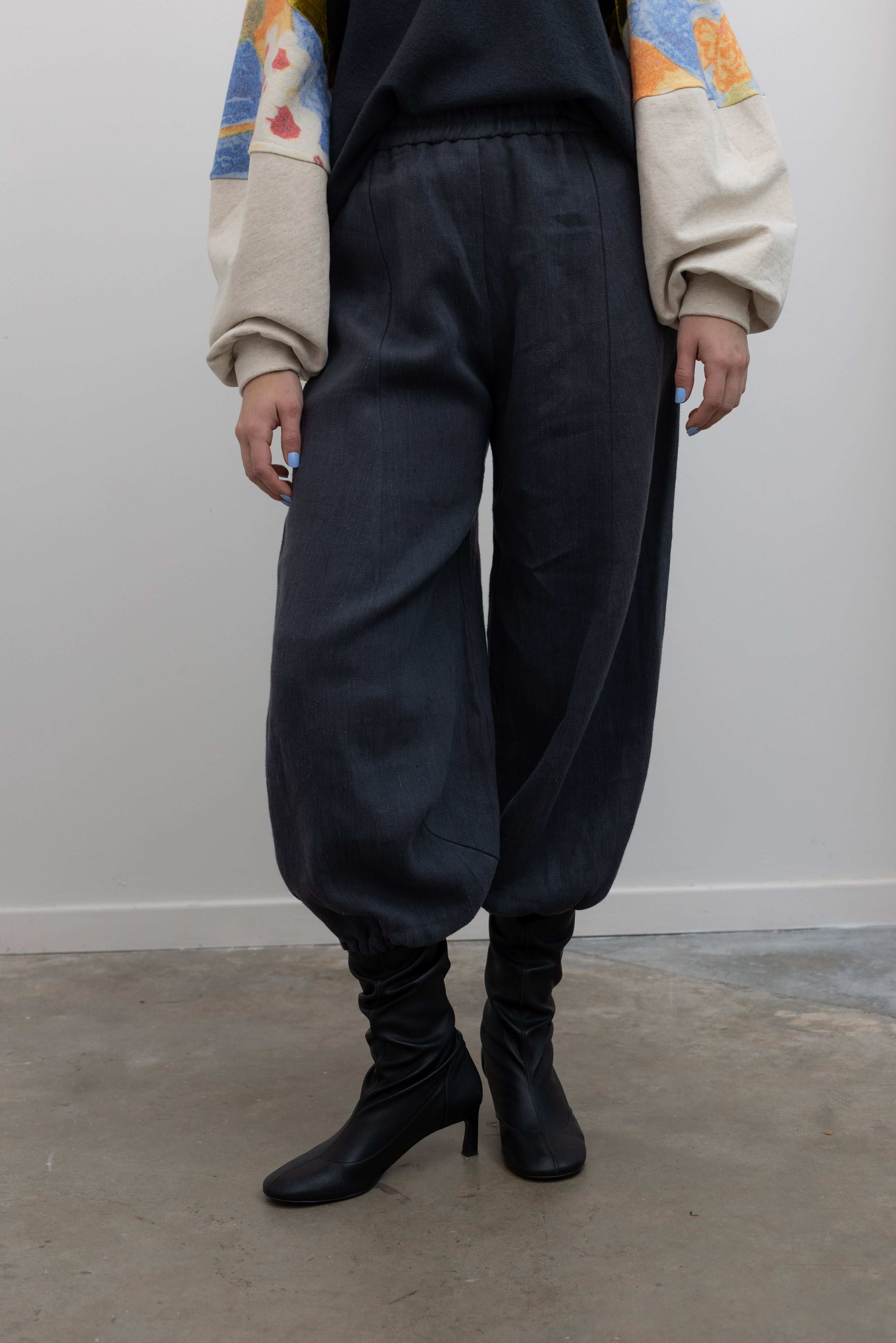 Person wearing dark blue pants and black boots against a plain background