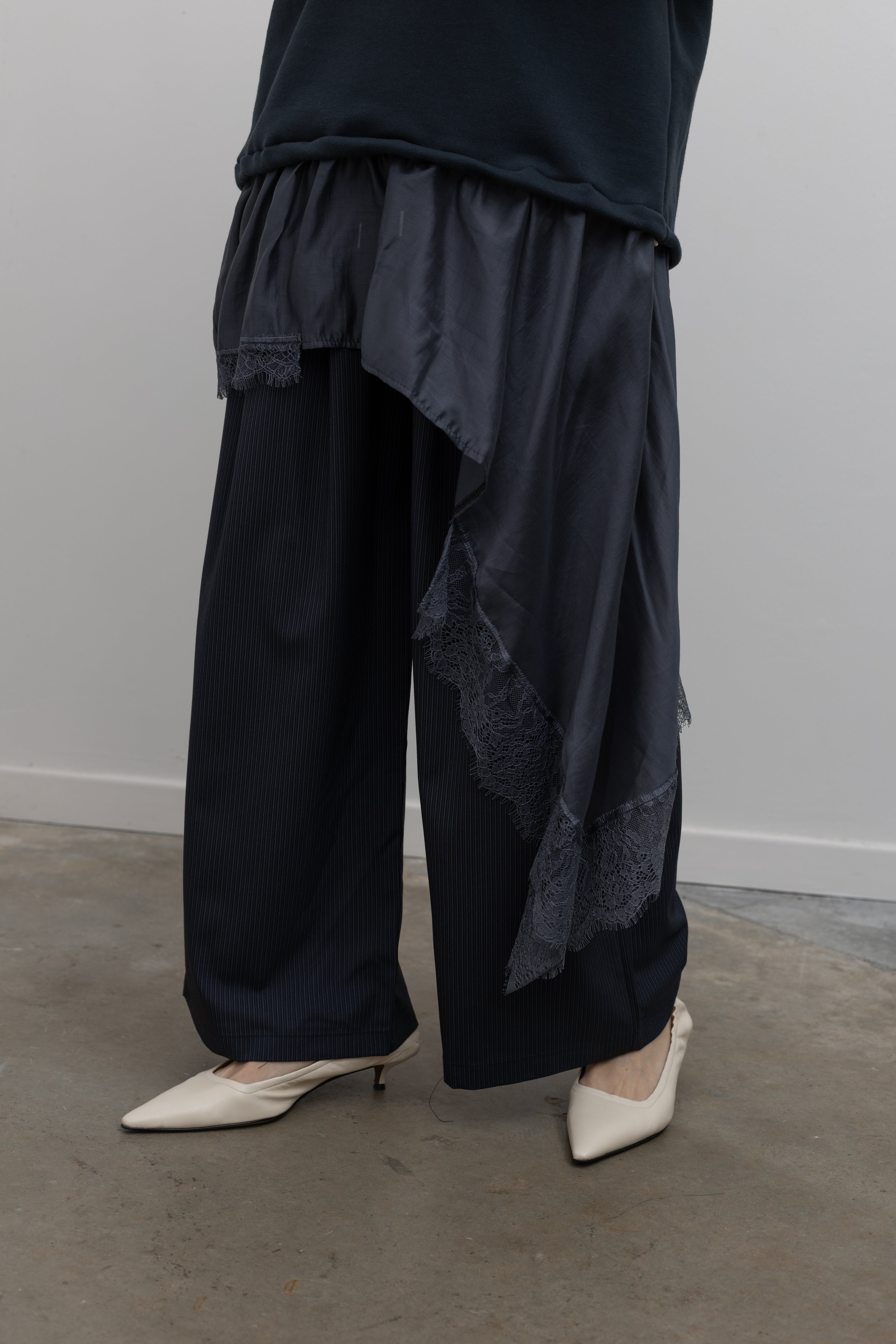 Product view of Woman standing wearing Spring fashion in a Collective Navy Lace Trim Cotton Oversized Jumper and navy blue pinstripe trousers with white pumps at Alas Eius 