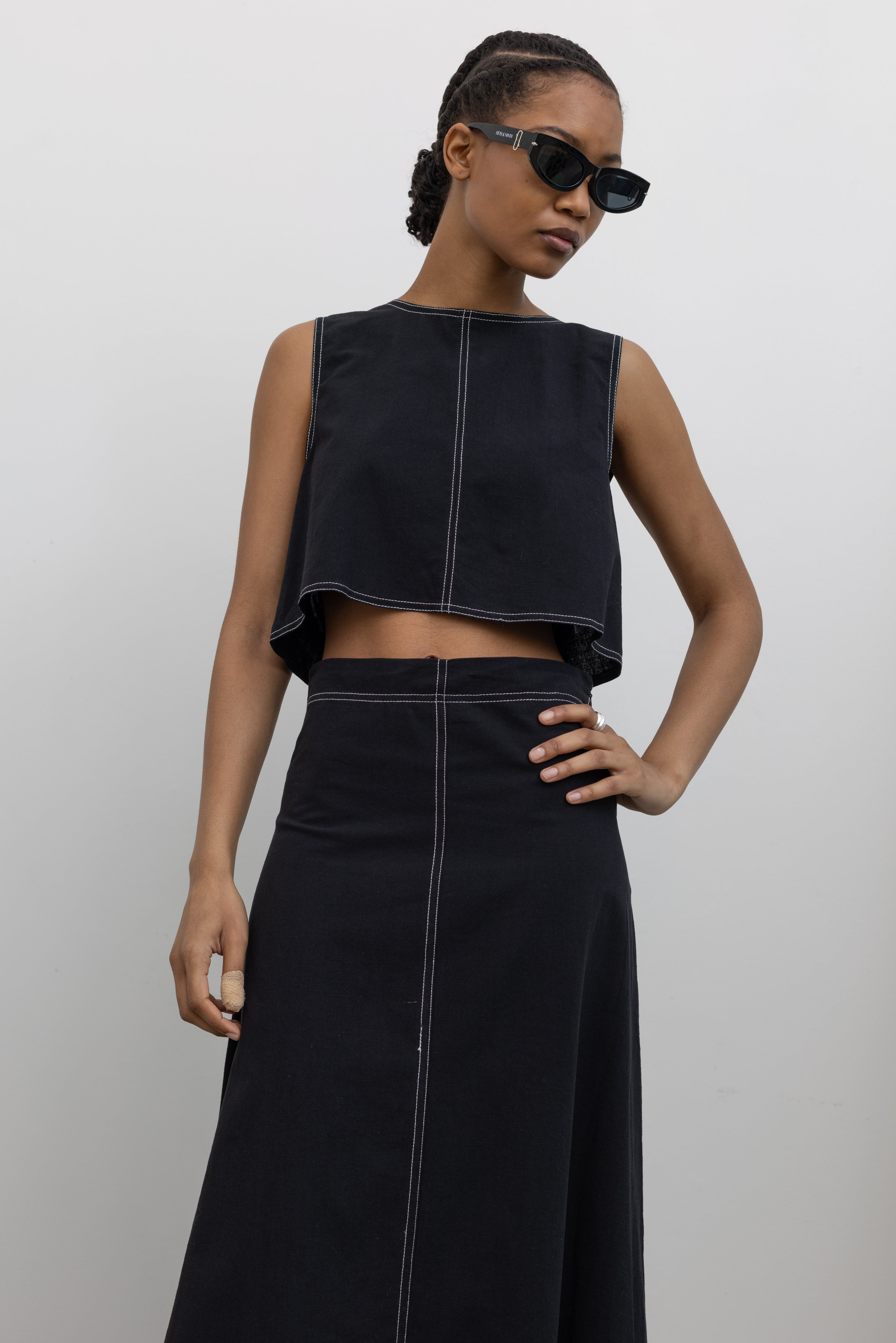 Woman posing with hand on her hip wearing Spring/Summer fashion in a 
Collective Black Cotton Linen White Contrast Stitch Cropped Top paired with a matching midi skirt to create a flattering set at Alas Eius.