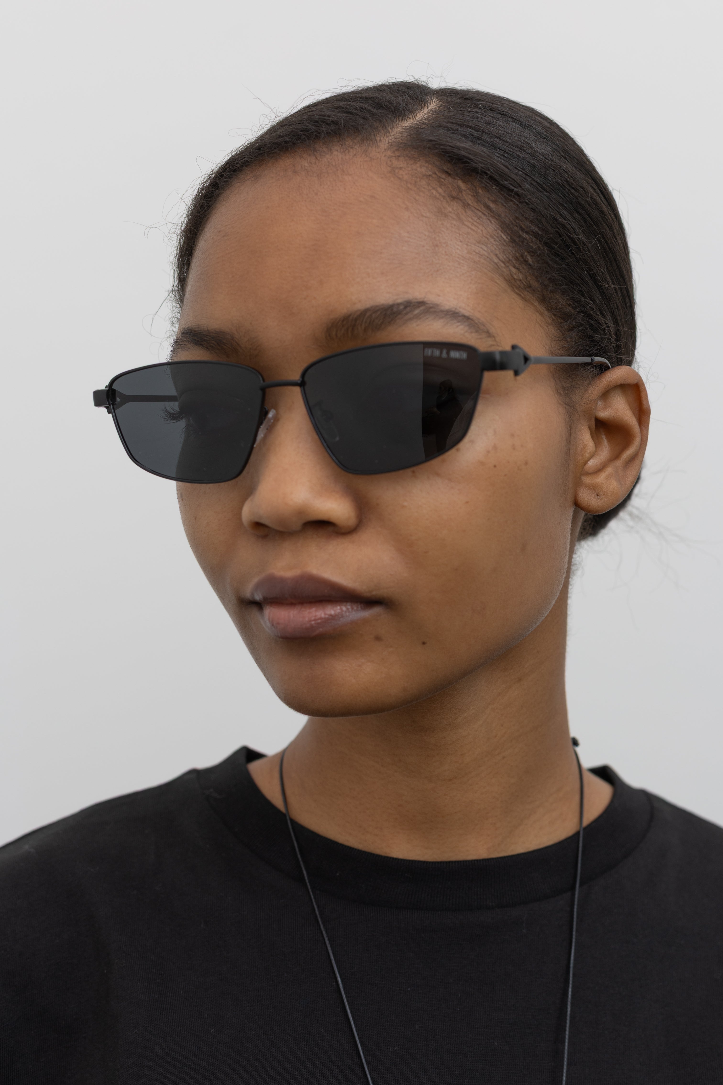 Woman wearing Collective brand black slim metal frame sunglasses at Alas Eius.