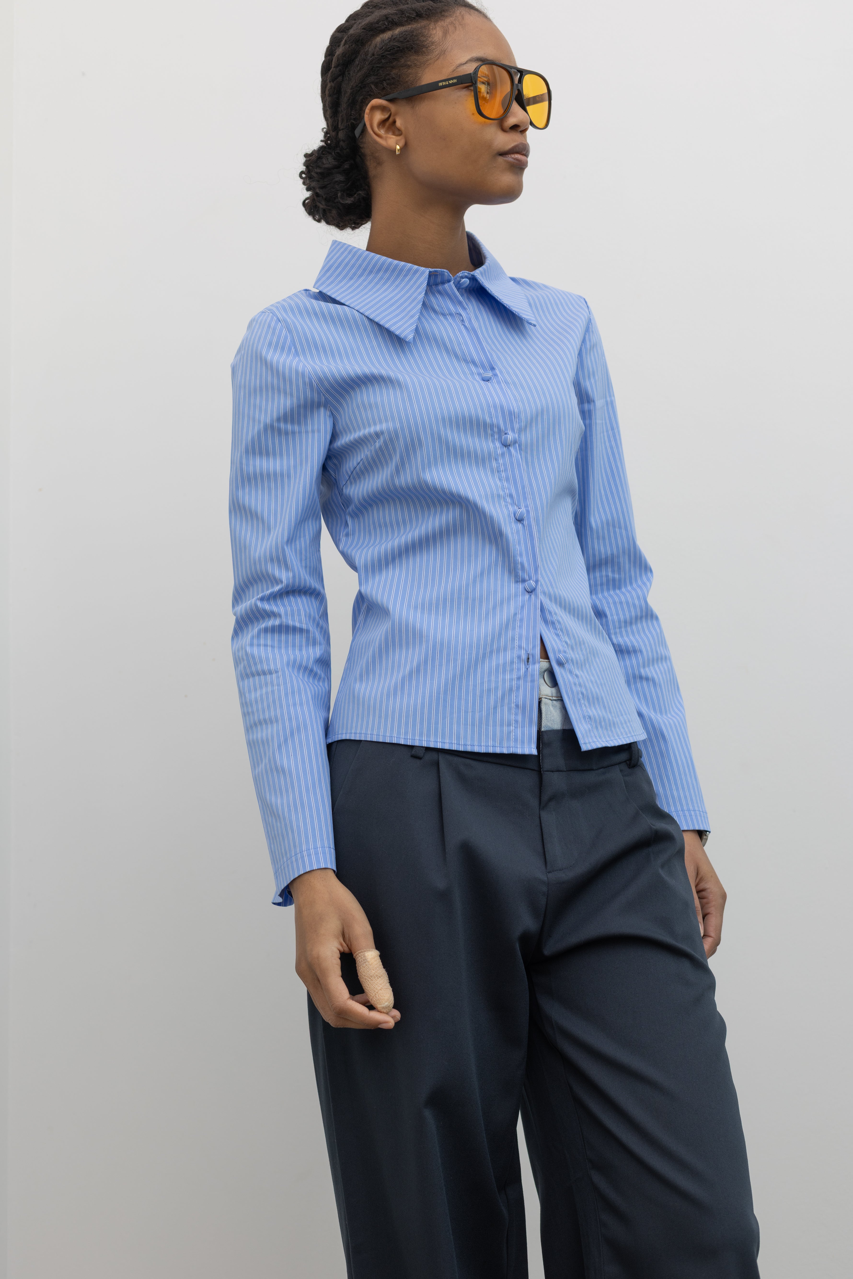 Side view of a woman wearing Spring fashion in a Collective Blue Pinstripe Tailored Slim-Fit Button Down Shirt with flared sleeves and fabric covered buttons at Alas Eius.