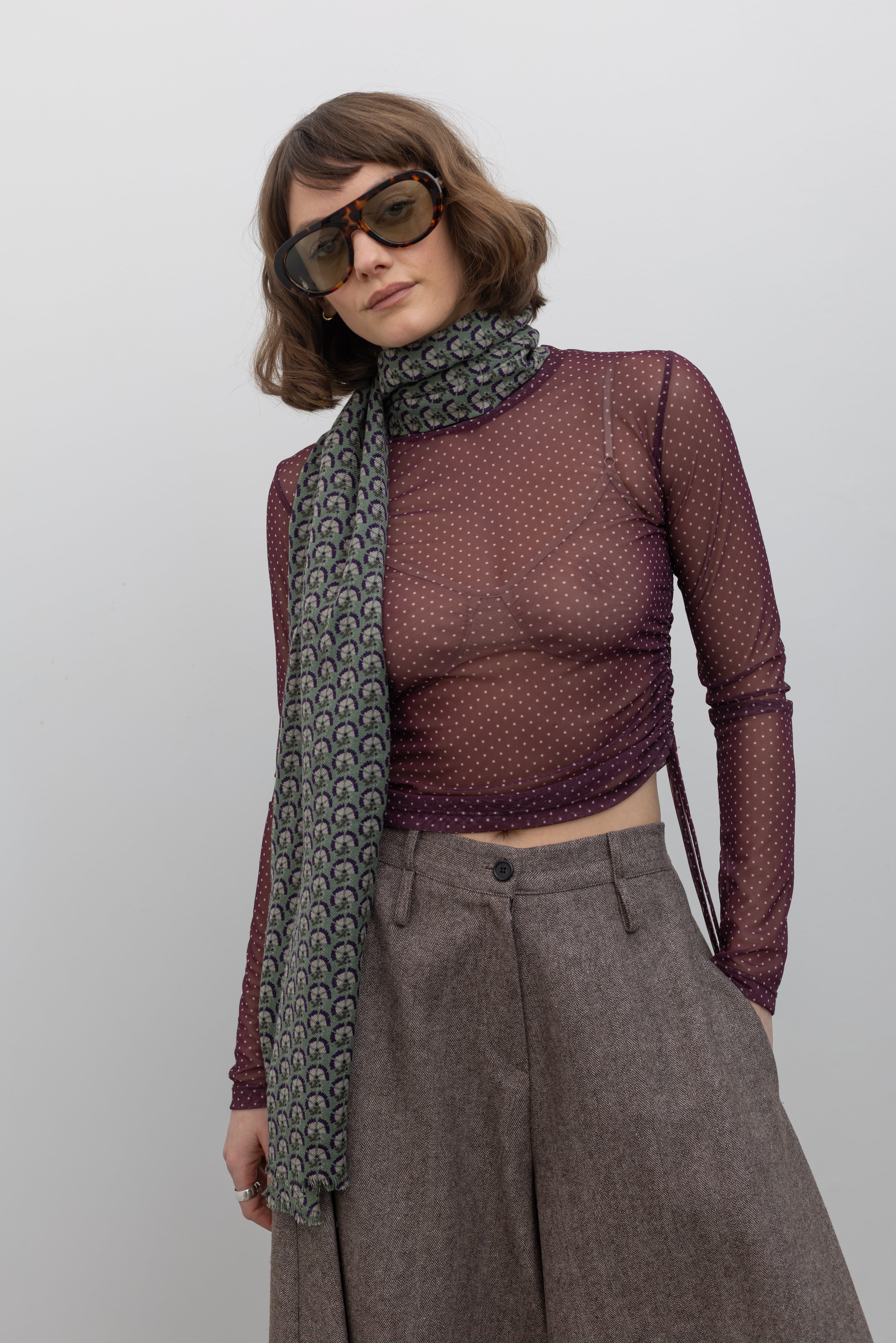Front view of a Woman wearing Collective Brown wool Herringbone Wide Leg Culotte Pants with a Les Belles Vagabondes brand Marigold green wool printed scarf at Alas Eius.
