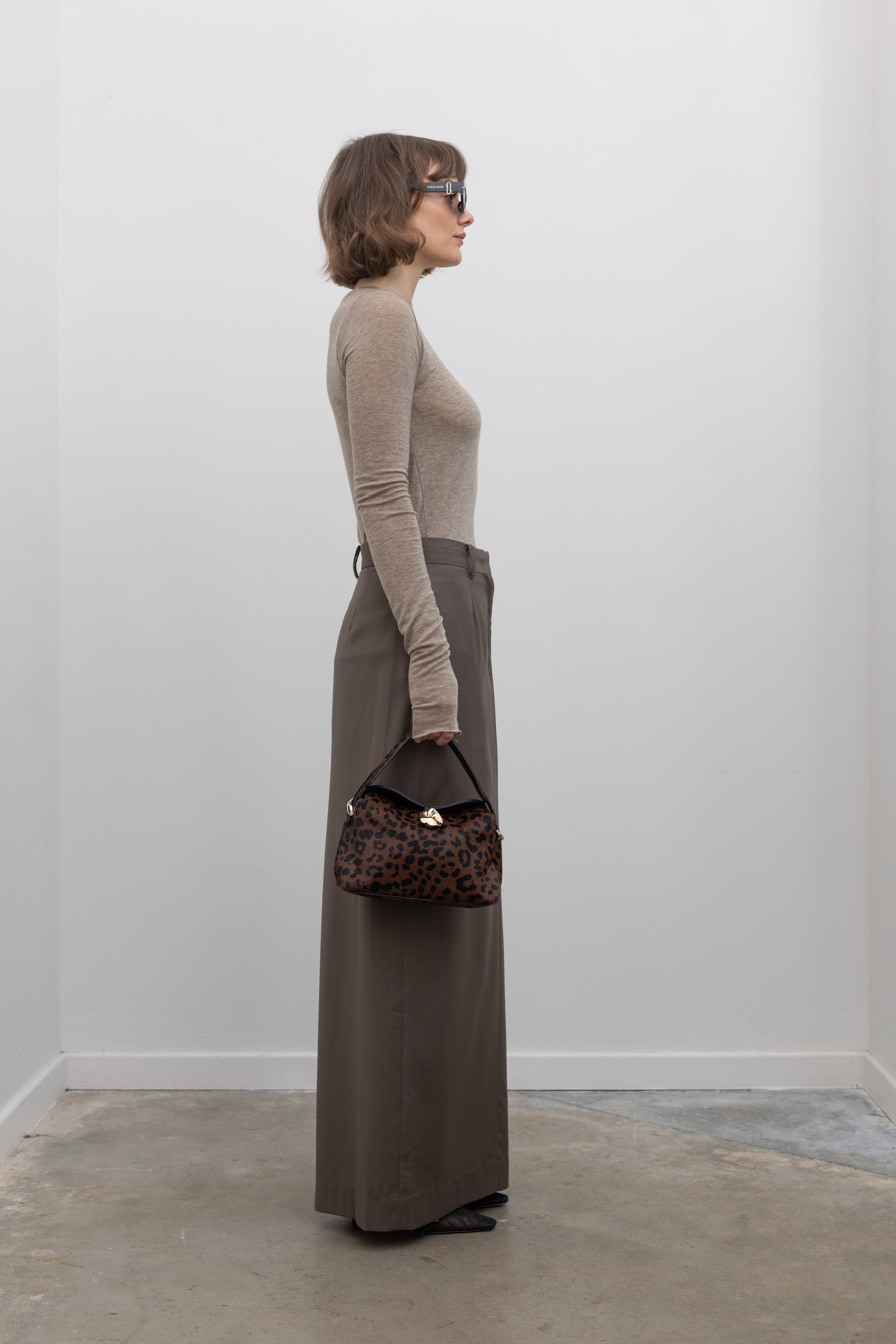Full length side view of a woman wearing an elevated capsule wardrobe essential in a Collective Brand Beige Merino Wool Long Sleeve Fitted Top at Alas Eius. 