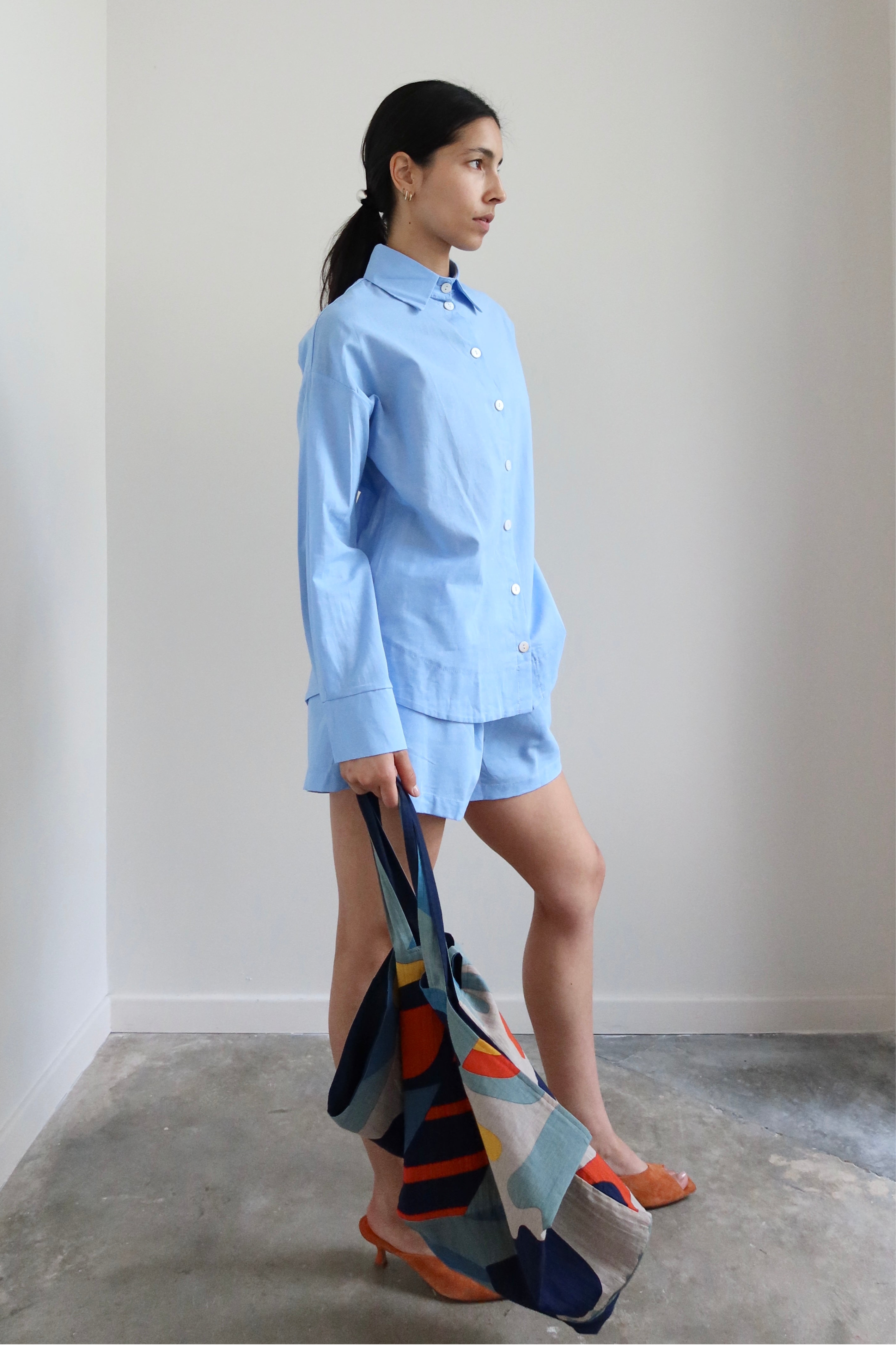 Full length side view of a woman wearing Spring / Summer fashion in a pair of Collective Light Blue Cotton Pull On Shorts at Alas Eius. 