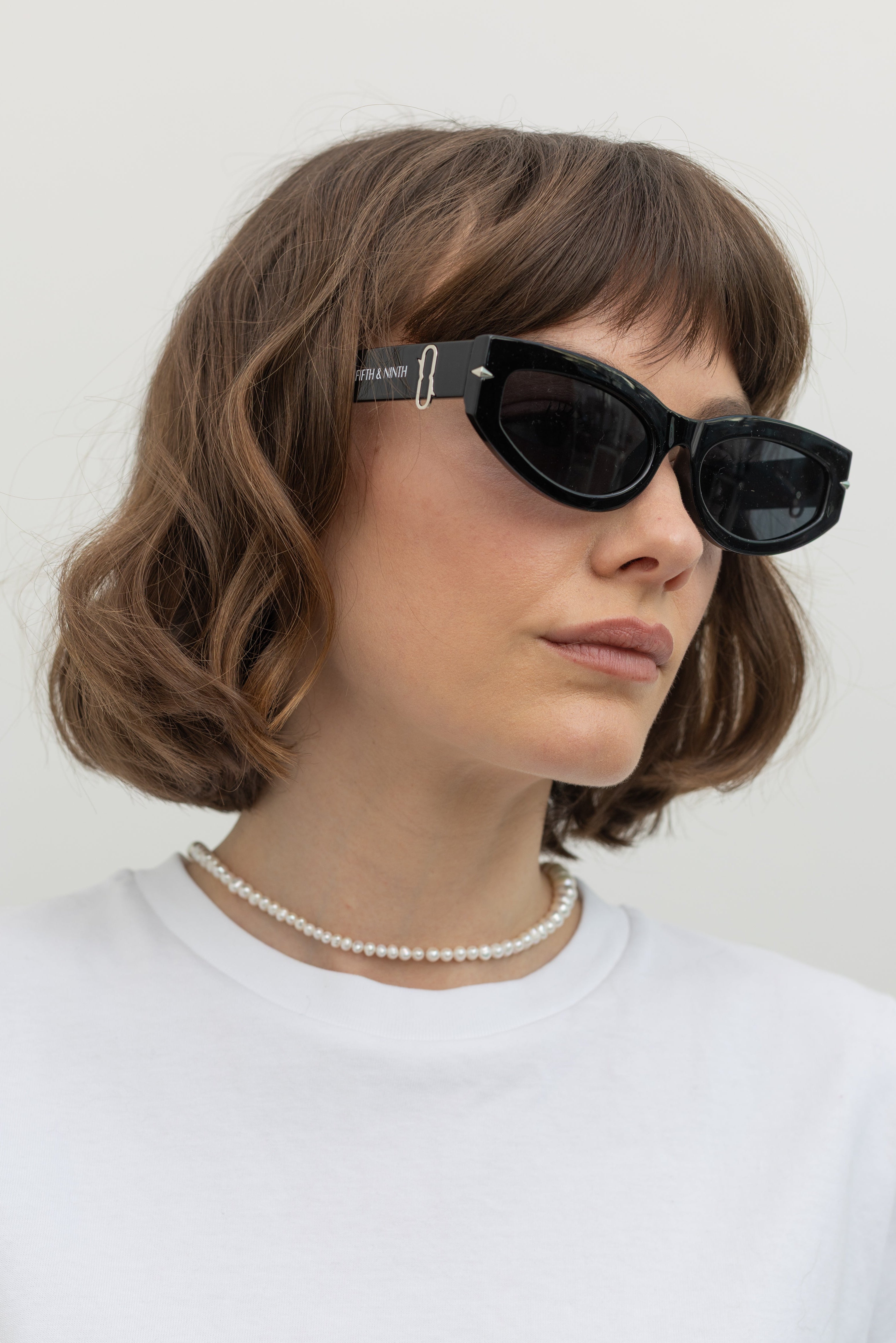 Side view of a woman wearing Collective label Black and Silver rectangle thick frame sunglasses at Alas Eius