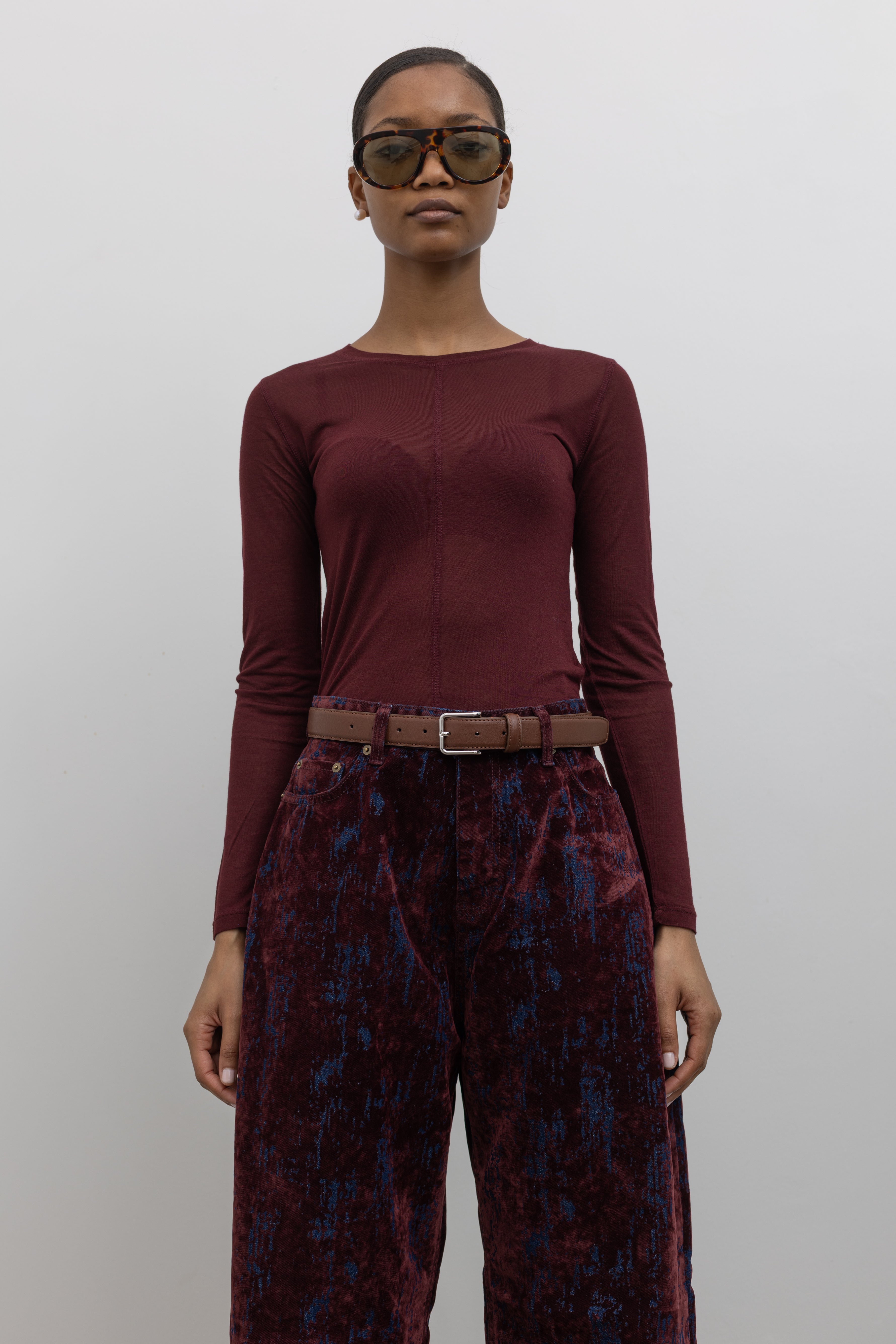 Woman wearing a capsule wardrobe essential accessory in a Collective brand classic brown leather belt made with a silver square shaped buckle at an Alas Eius store. 