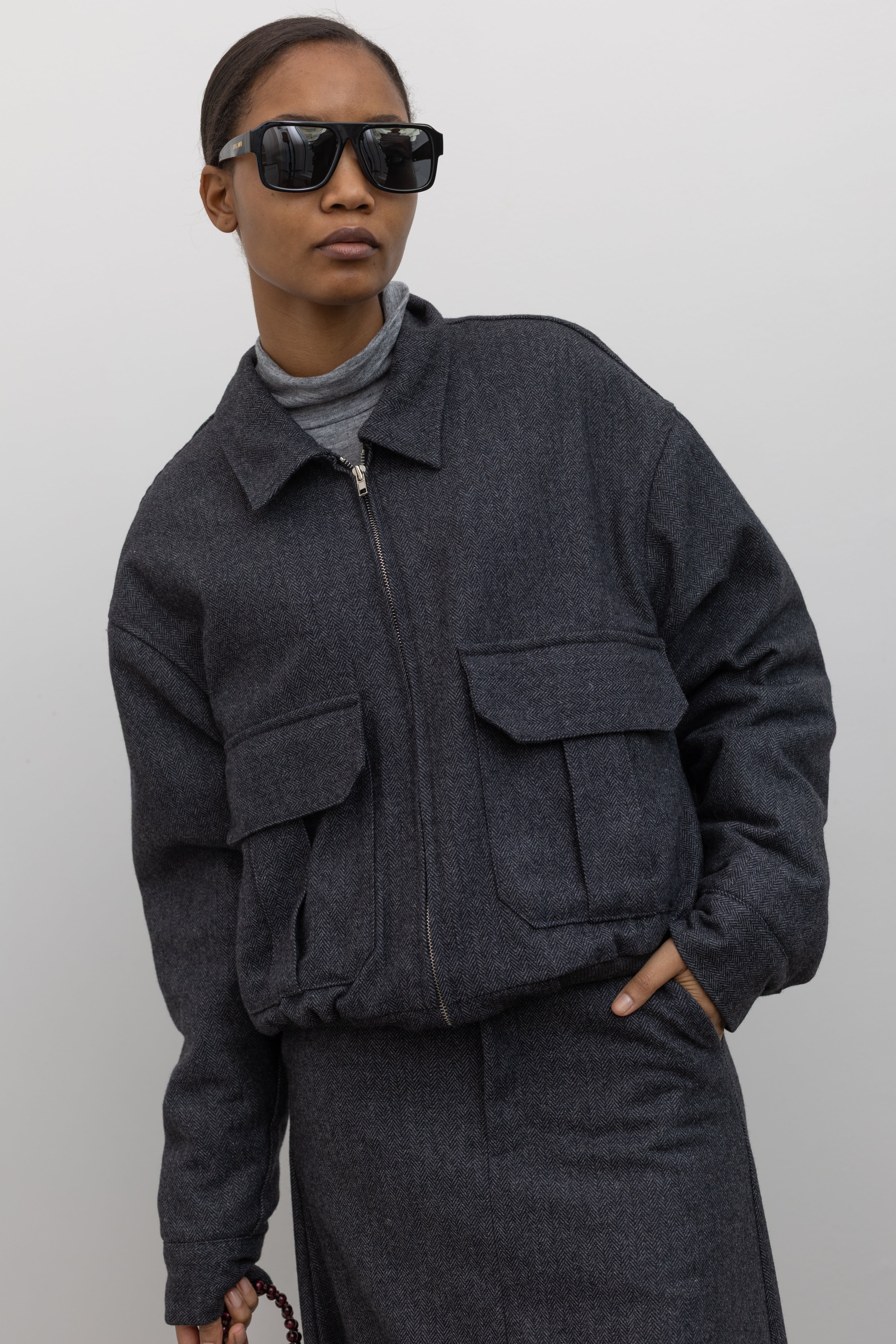 Close-up product view of a Collective Charcoal Wool Blend Herringbone Collared Quilted Bomber Jacket at Alas Eius.