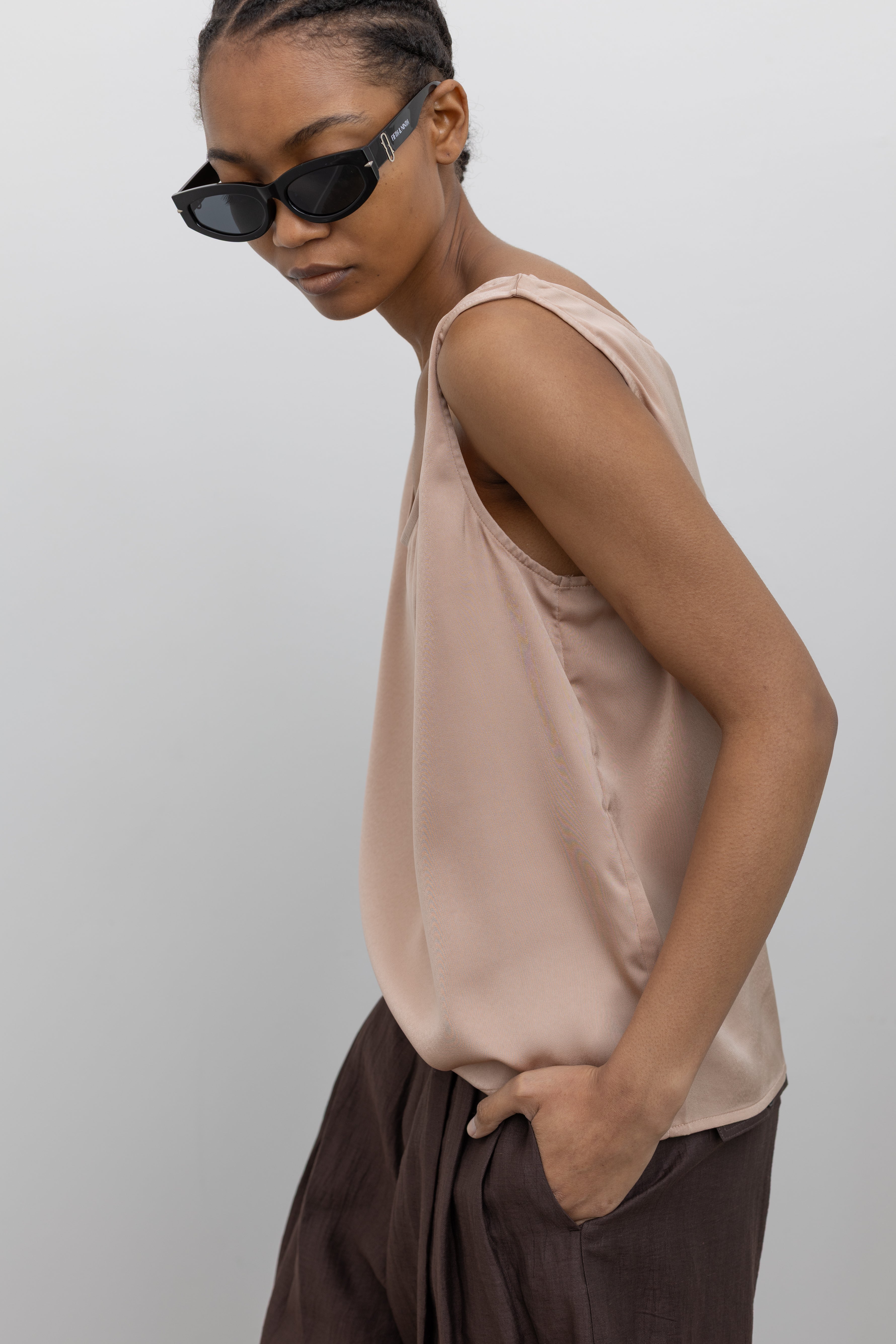 Close-up view of a woman wearing Spring fashion in a Collective brand solid beige satin tank top with a relaxed flowy fit paired with pleated trouser at Alas Eius.