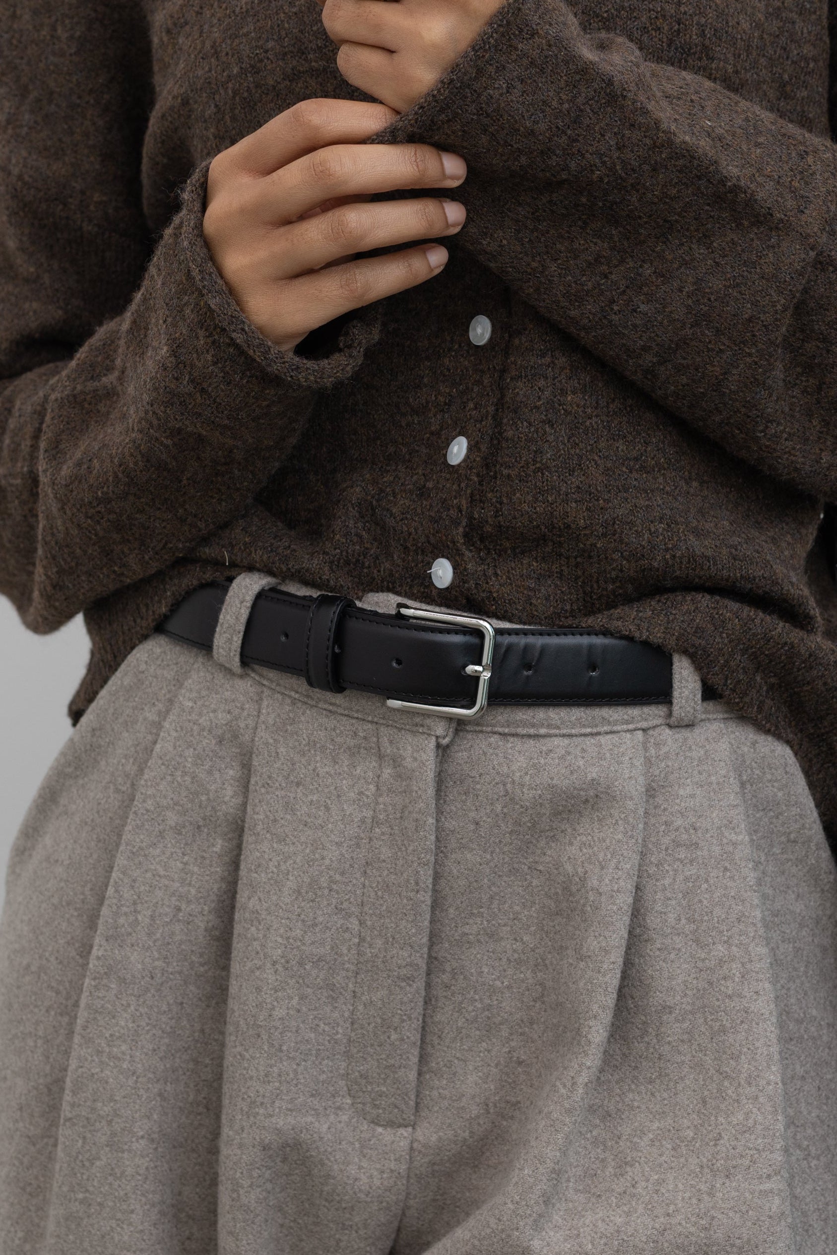 Collective Classic Black Leather belt with silver square buckle paired with a classic wool button front cardigan and gray pleated trousers at Alas Eius 