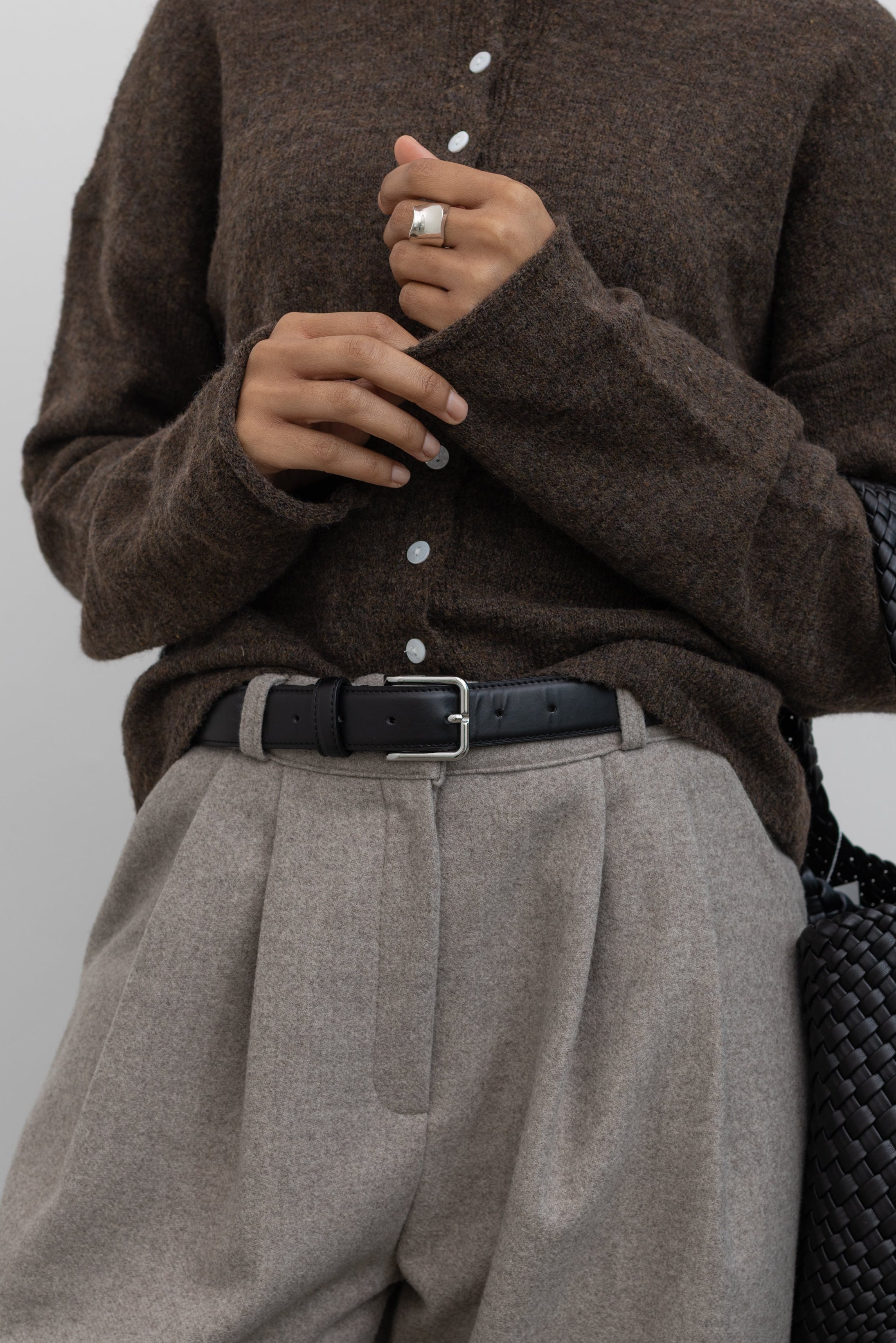 Collective Classic Black Leather belt with silver square buckle paired with a classic wool button front cardigan and gray pleated trousers at Alas Eius 