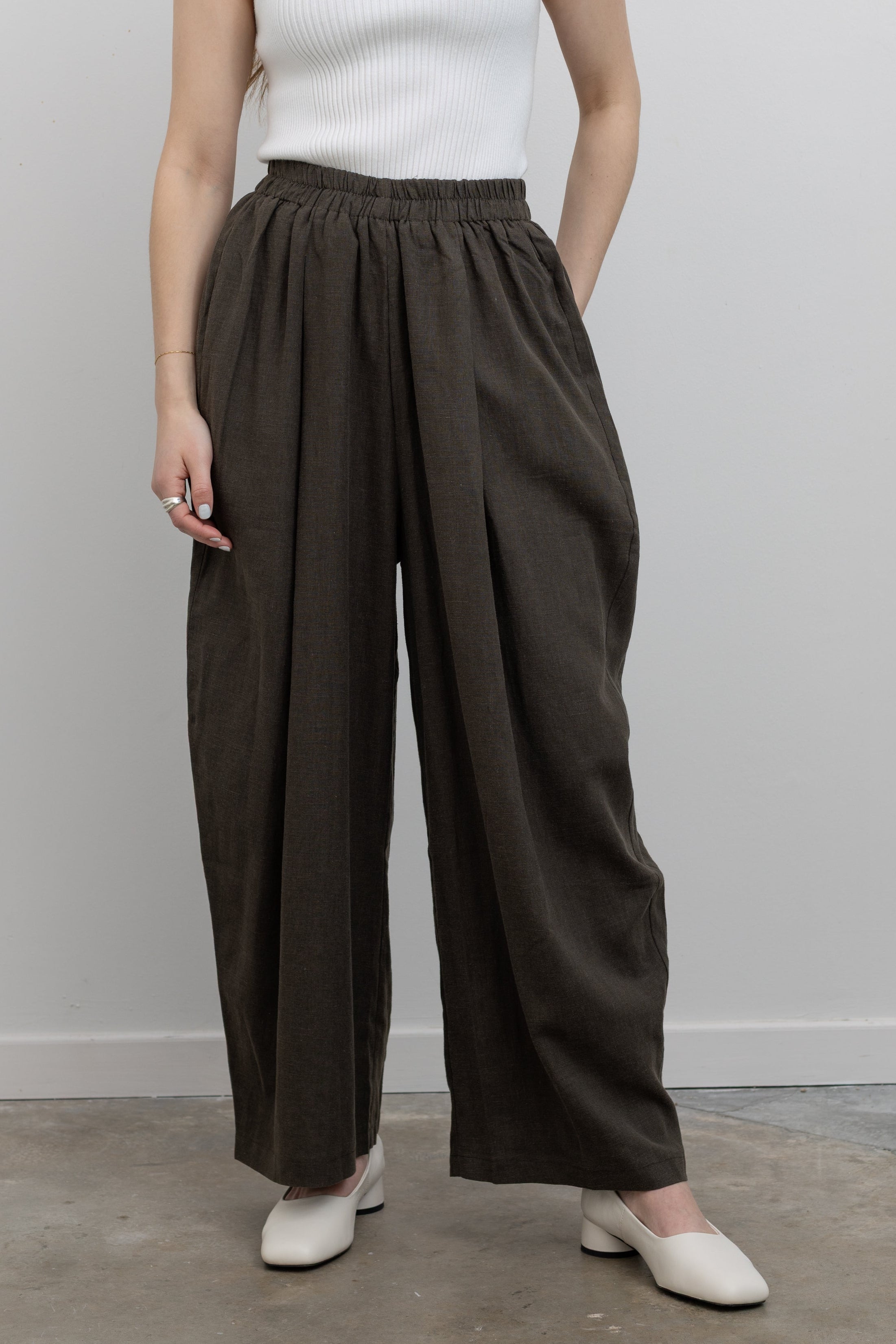 Product front view of woman standing wearing Spring fashion in a pair of Collective Coffee Elastic Waist Billow Trousers at Alas Eius 