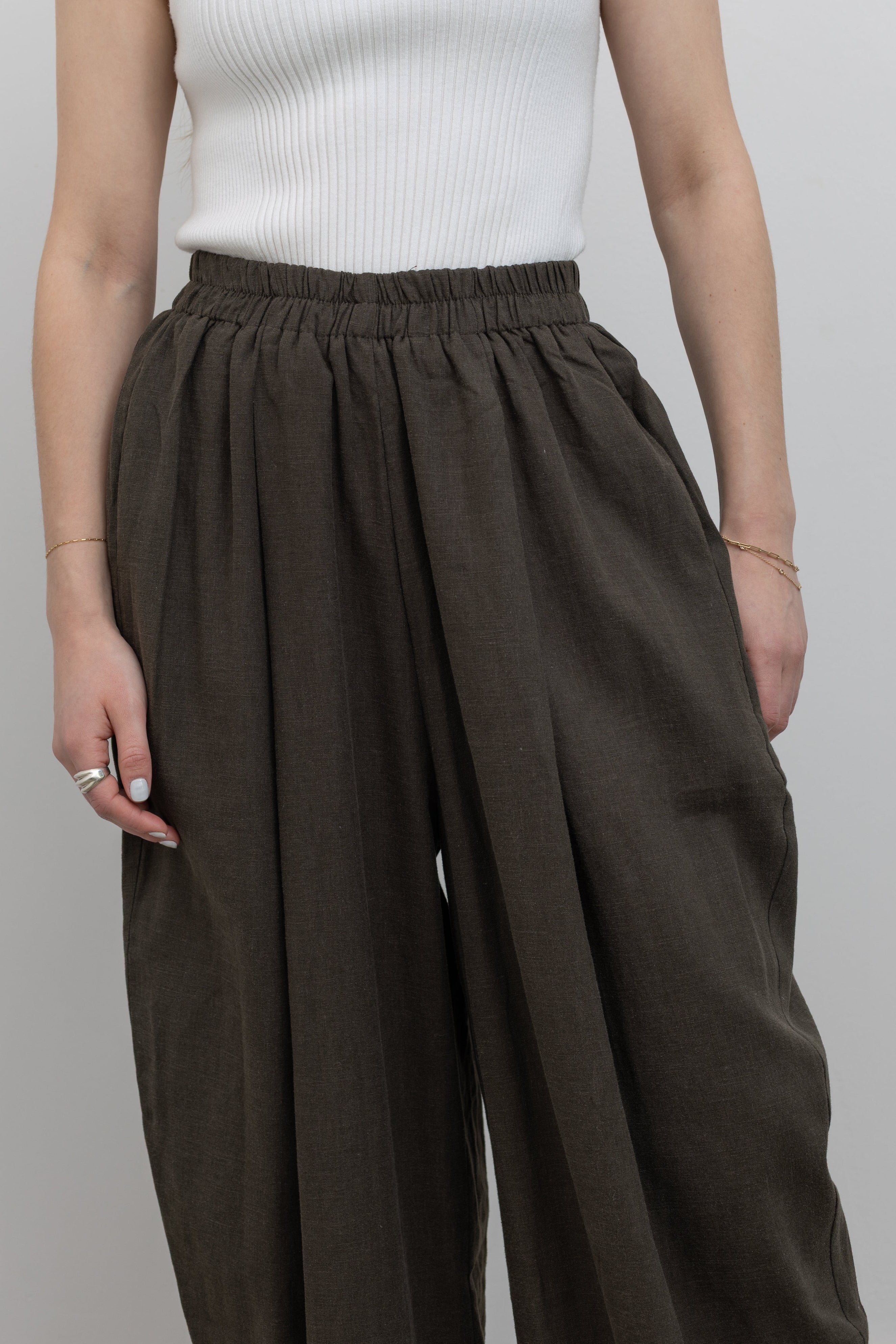 Detailed product front view of woman standing wearing Spring fashion in a pair of Collective Coffee Elastic Waist Billow Trousers at Alas Eius 