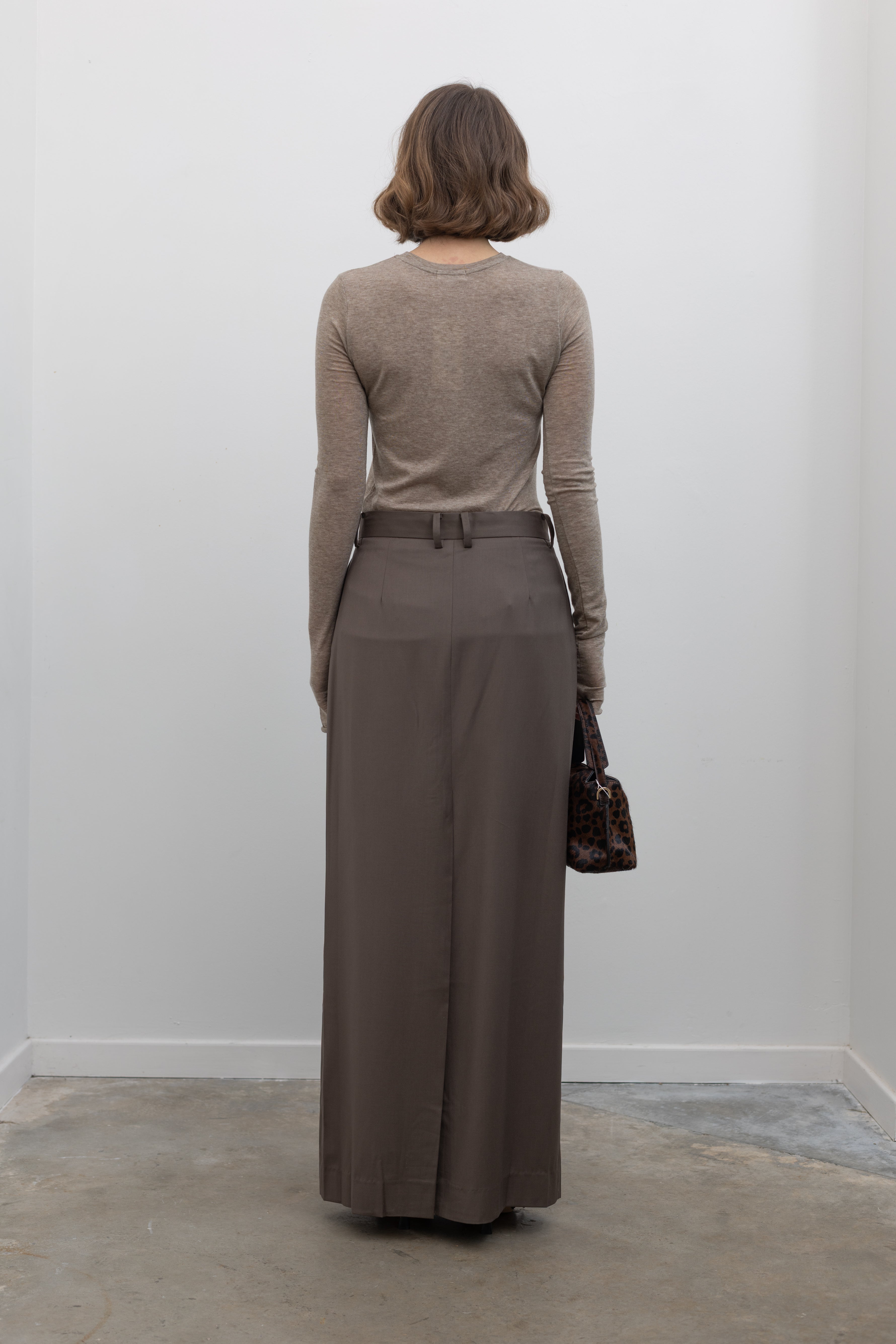 Back view of a woman wearing an elevated capsule wardrobe essential in a Collective Brand Beige Merino Wool Long Sleeve Fitted Top at Alas Eius. 