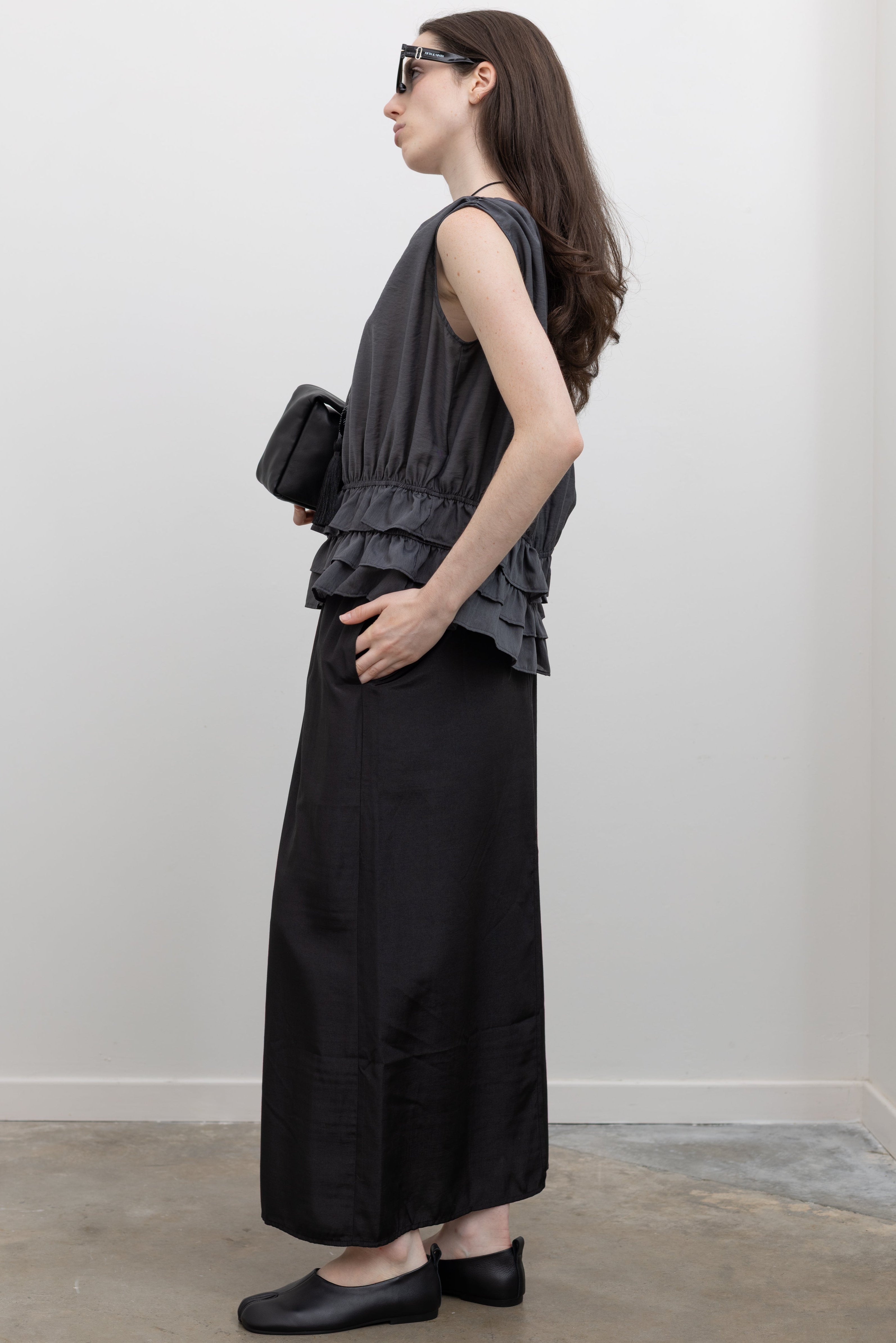 Collective women’s sleeveless blouse with elastic shirring at the waist, sculptural tiered ruffle hem, and lightweight draped Tencel fabric for modern chic outfits at Alas Eius