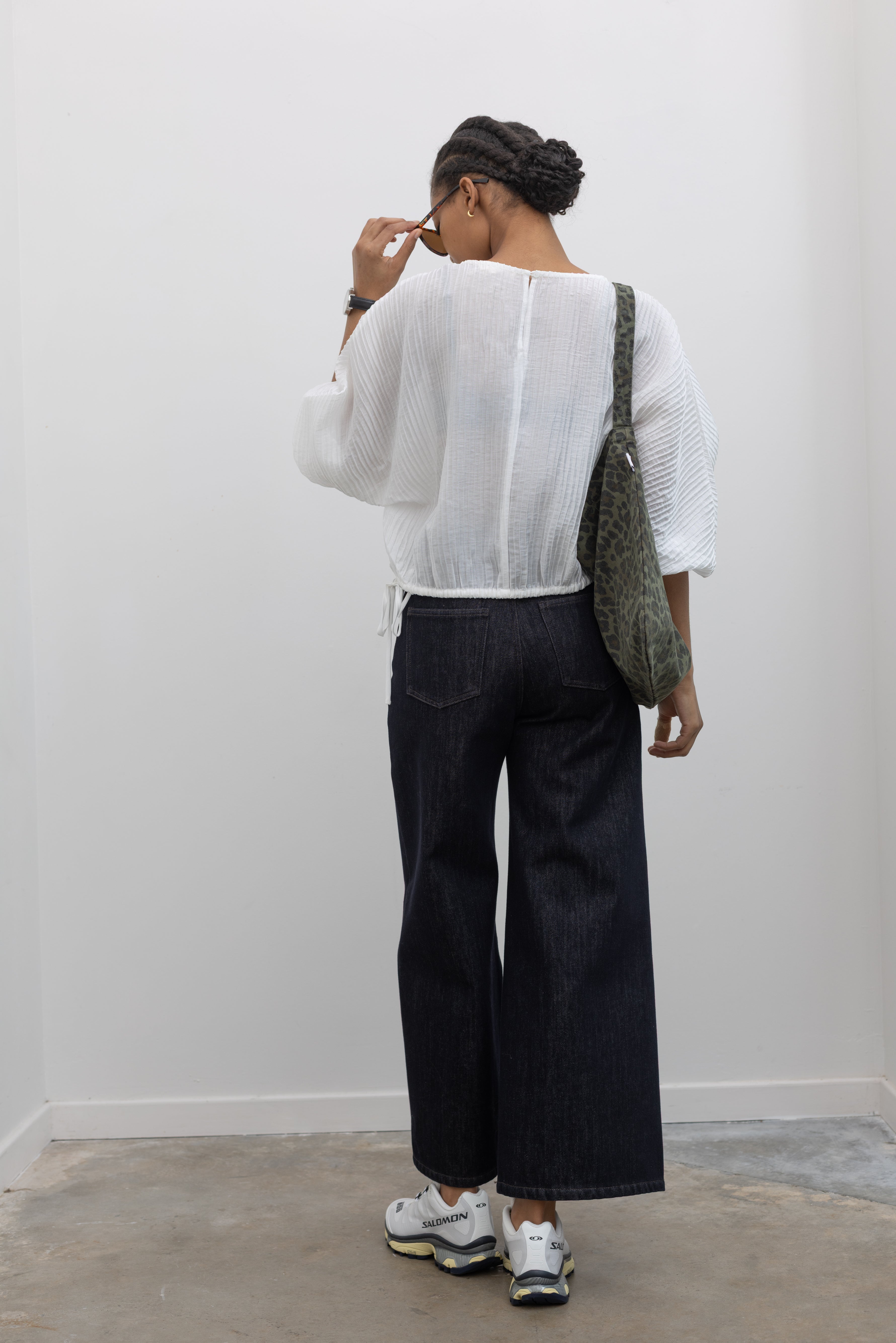 Back view of a woman wearing Collective brand dark wash fleece lined wide-leg, high-rise jeans with squared off pockets with silver hardware and a white top at Alas Eius.