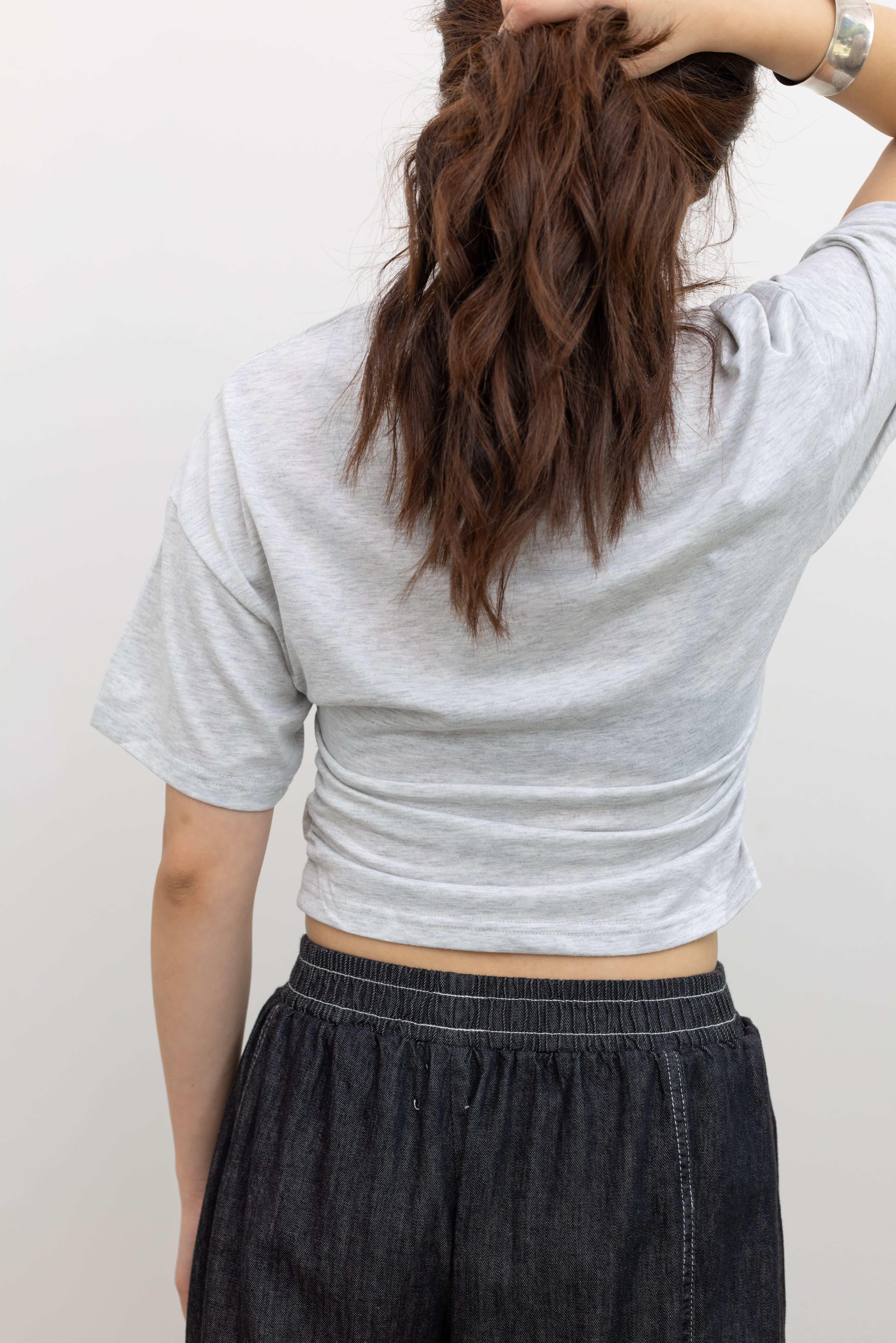 Woman in a Collective light gray batwing cropped tee and Alas Eius black contrast stitch barrel jeans